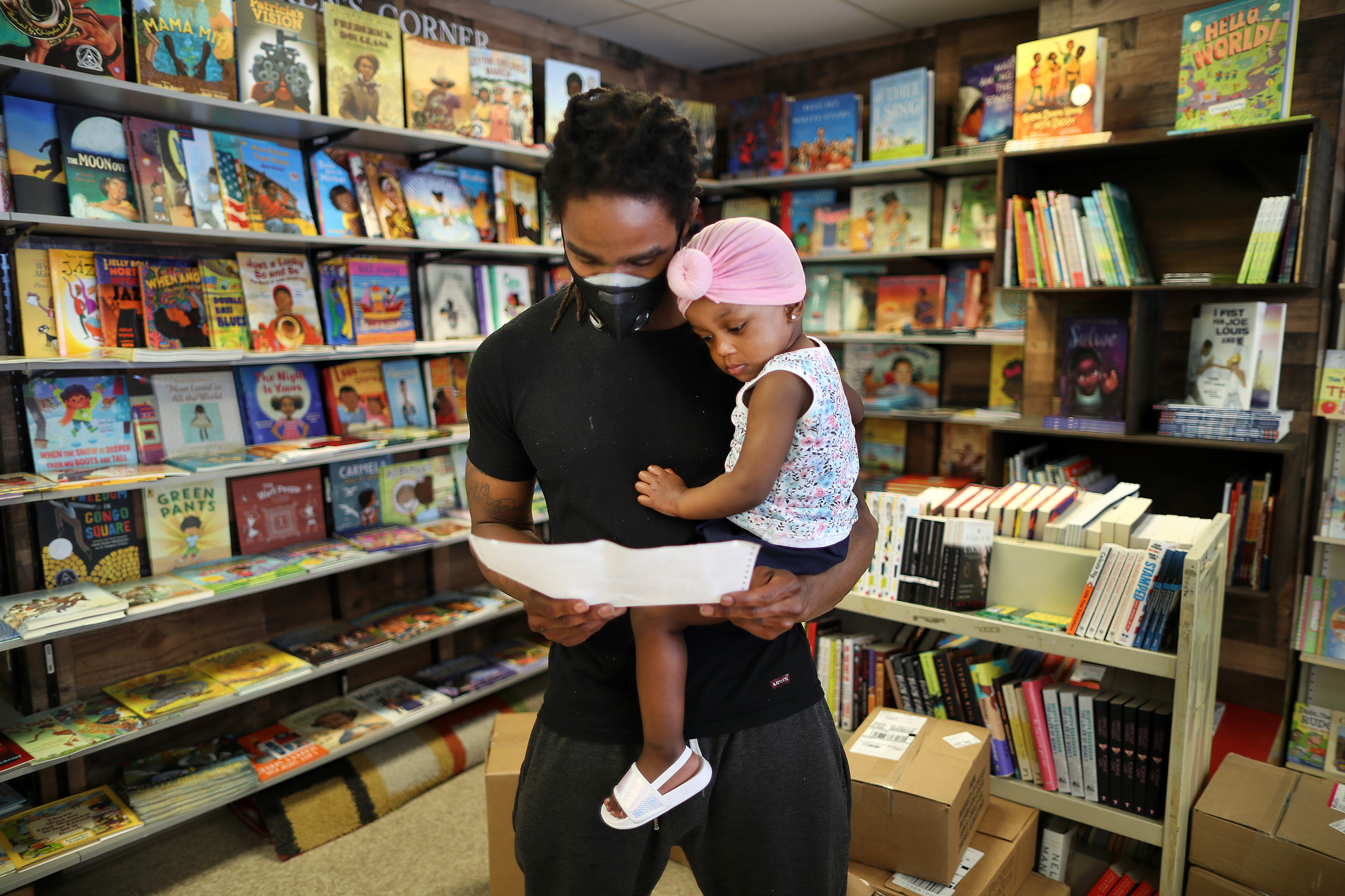 The Frugal Bookstore worker Eric Anderson held his daughter Unique as he checked on inventory inside the store in Roxbury.