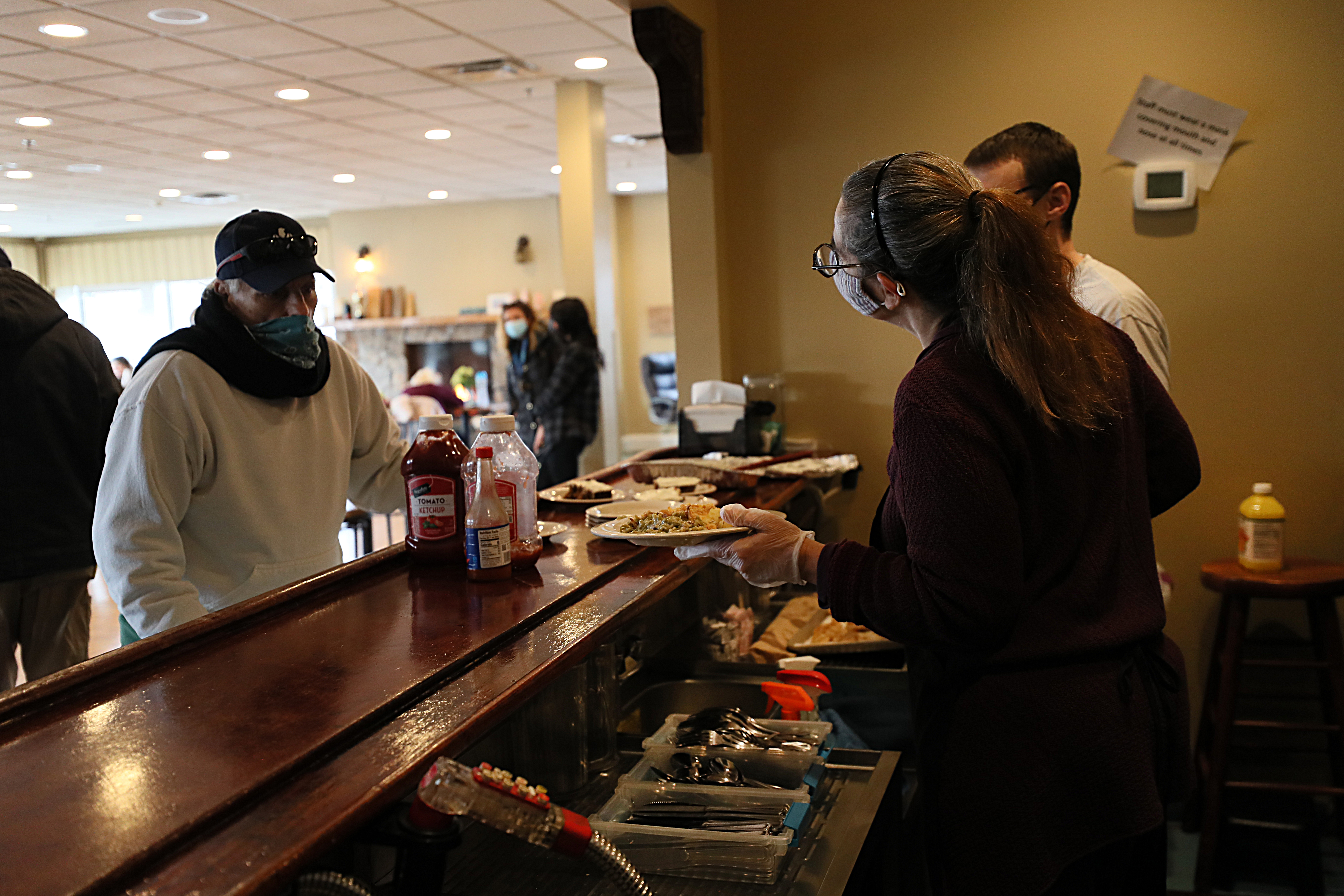 Volunteer Amanda Nash serves lunch to guests of the Grace Center from the bar of the temporarily closed Gloucester House Restaurant.