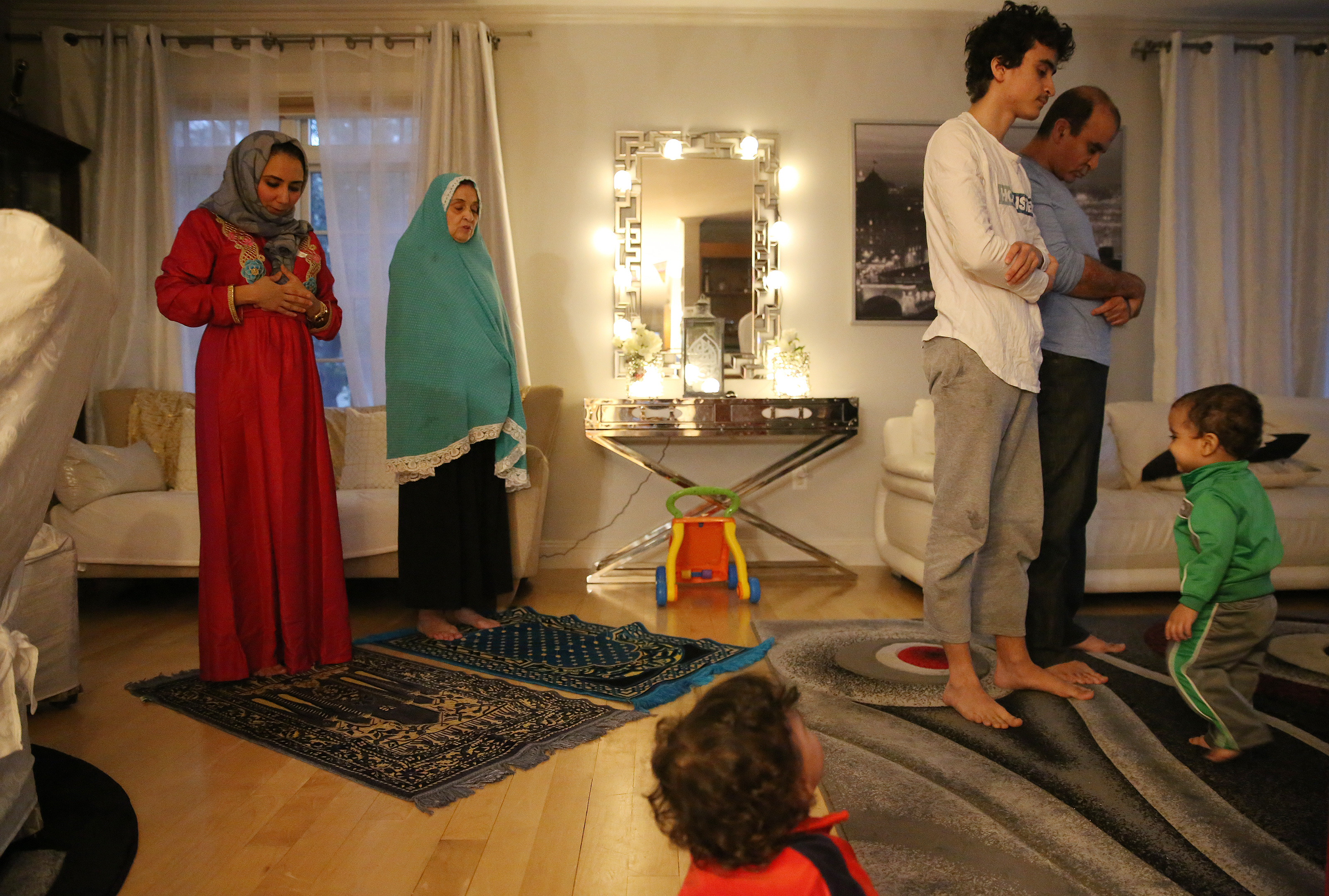 Chestnut Hill, MA - 5/3/20: (Back Row: L-R) Heba Algendy, and her mother-in-law, Nabila pray as one and a half year old twins Hassan (Bottom) and Seleem (R) watch their big brother, Hazem, 14, and their dad, Sharif, pray the Maghrib sunset prayer as the family breaks their fast during Ramadan. The Algendy's are observing Ramadan in quarantine because of coronavirus or COVID-19. (Jessica Rinaldi/Globe Staff)