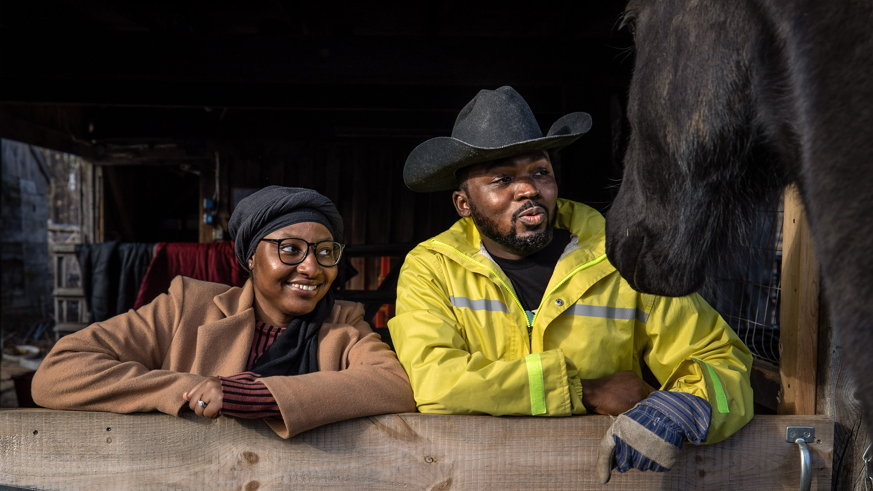 Ayo and Hameed Bello, owners of Agric Organics Urban Farm in Wilbraham, stood in their barn doorway while their horse Ryker tries to get some attention.