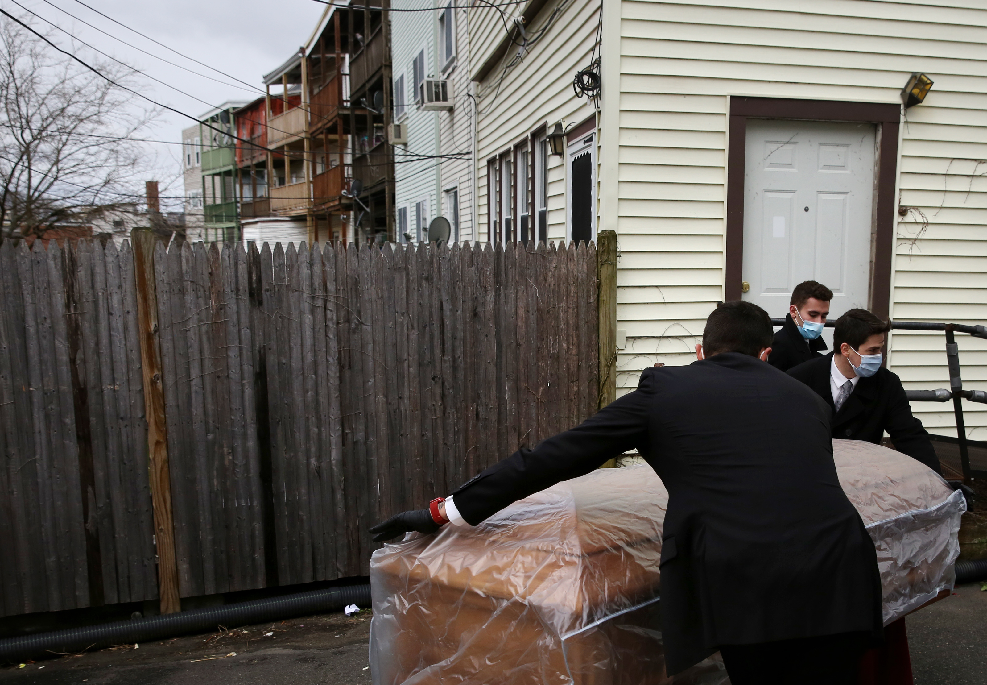 Matt Tauro, Nick Turco, and John Lockhead moved the casket of a woman who died of COVID-19 in East Boston to the hearse parked outside of Ruggiero Family Memorial Home.