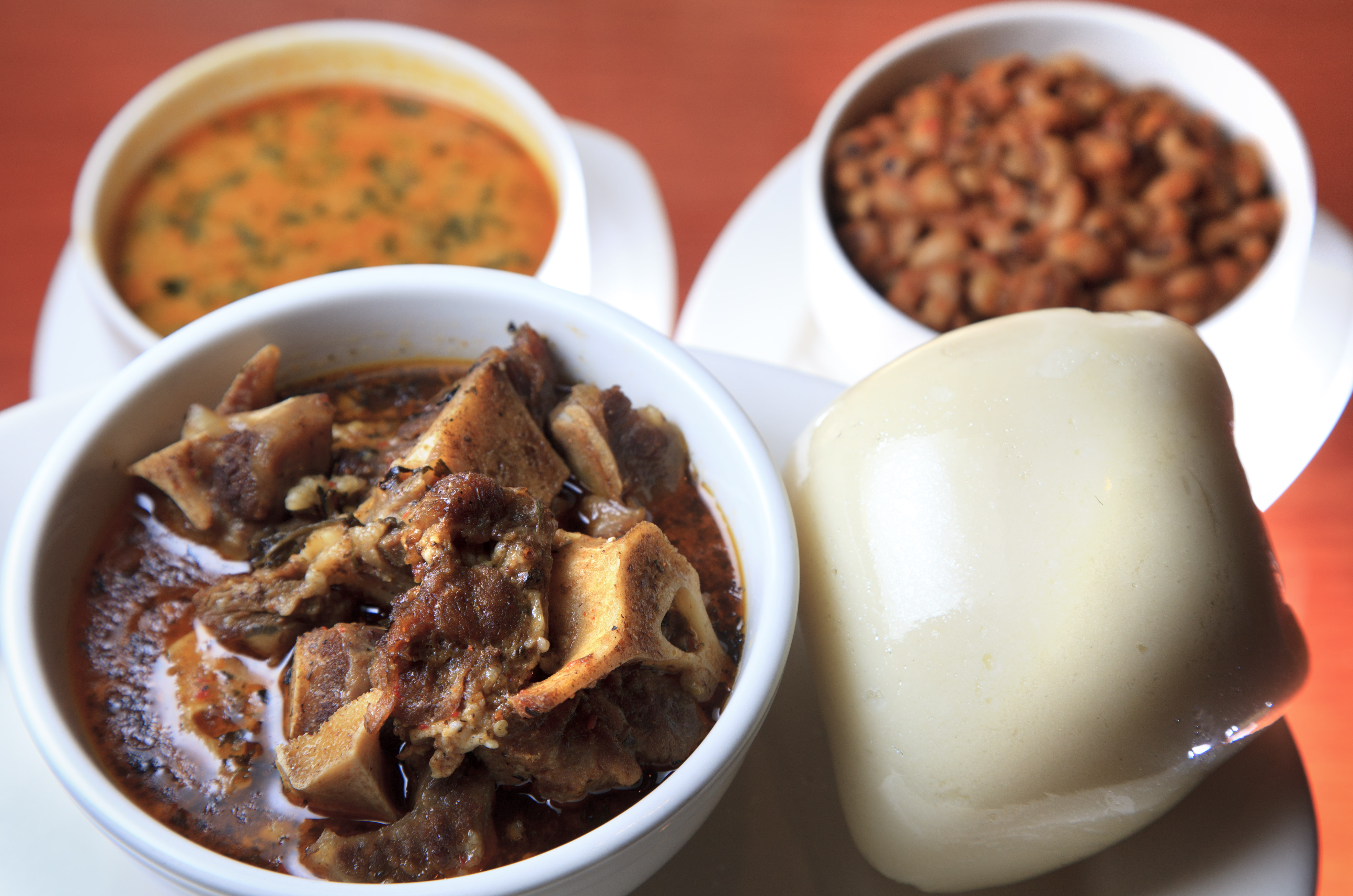 The Oxtain Pepper Stew at Suya Joint, shown with pounded yam fufu (at right), taushe (peanut soup) at back left, and stewed black eyed peas (back right).
