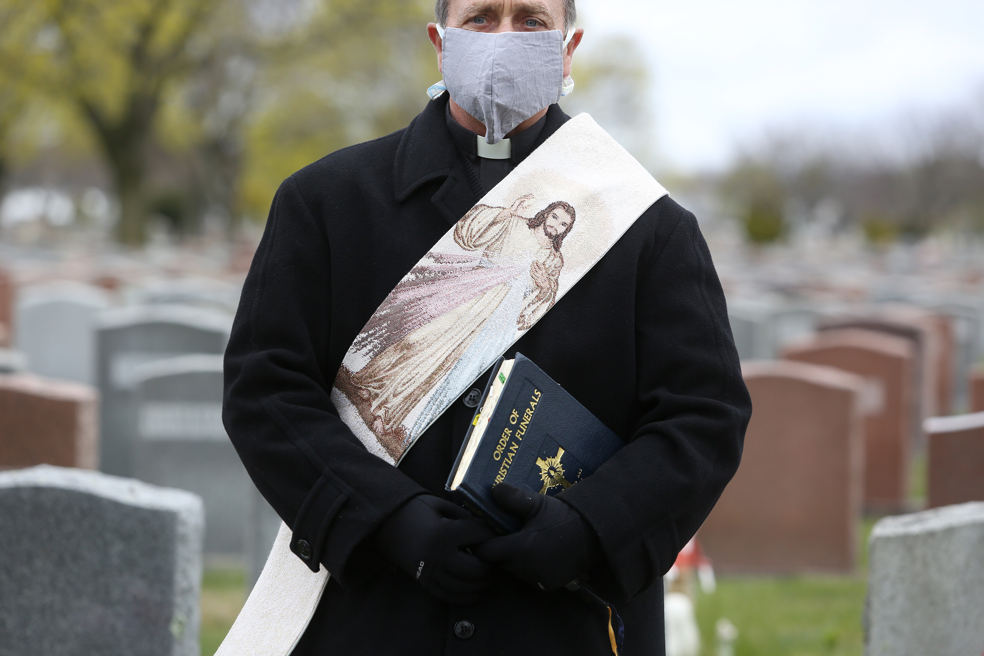 Jim Leo, a Deacon at St. John the Evangelist Church in Winthrop, stood beside the casket of a man who died of coronavirus as he waited for the family to arrive for a socially distanced graveside service.