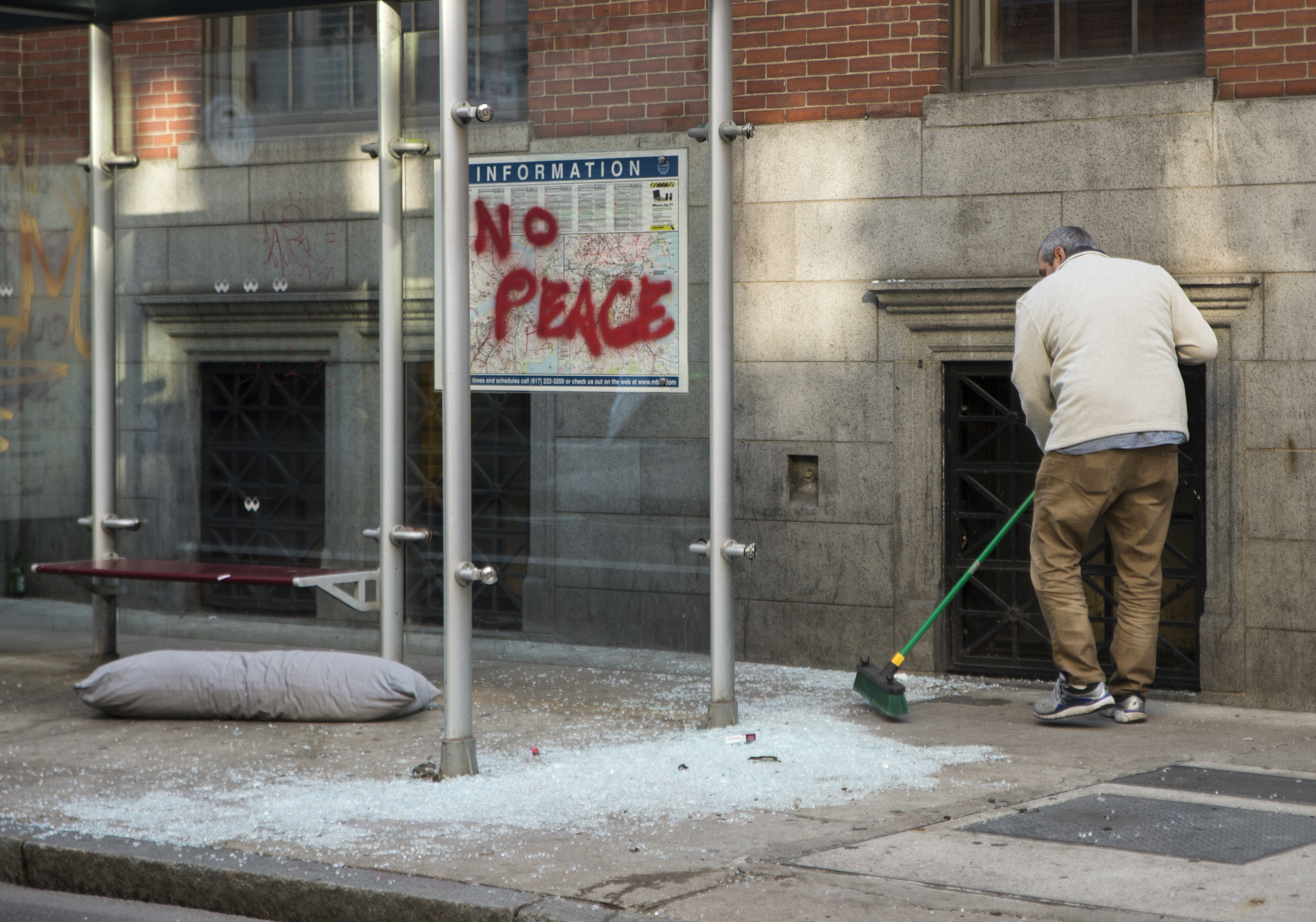 A man swept up glass from the shattered pane of a bus stop as crews worked to clean up glass and debris in Downtown Crossing, near Tremont Street.