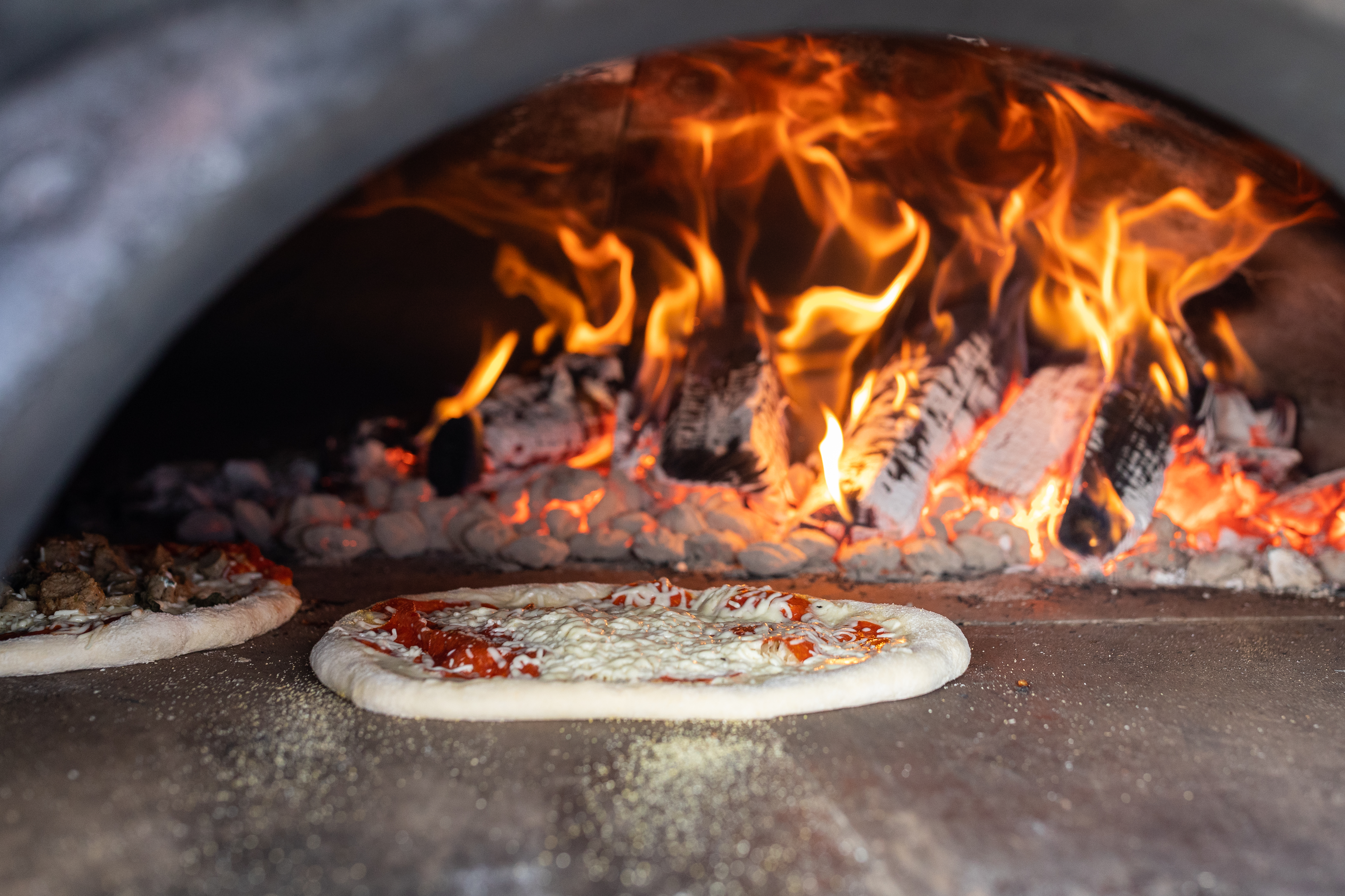 Two pizzas cook inside an outdoor pizza oven retired Middleton Police Chief Jim DiGianvittorio got from Italy.