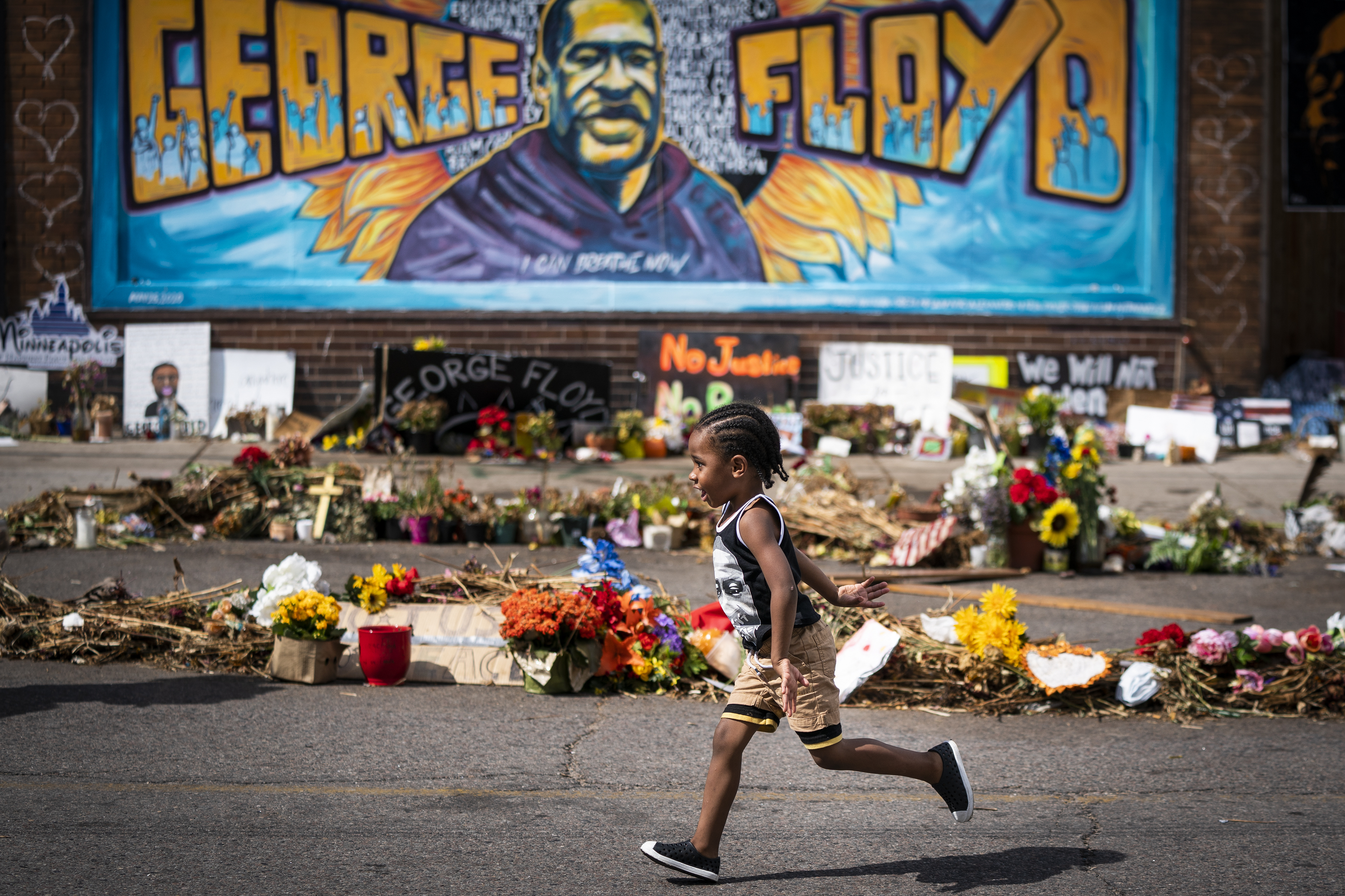 Carter Sims, 3, of Pine Island, Minn., runs past a mural at the George Floyd memorial.