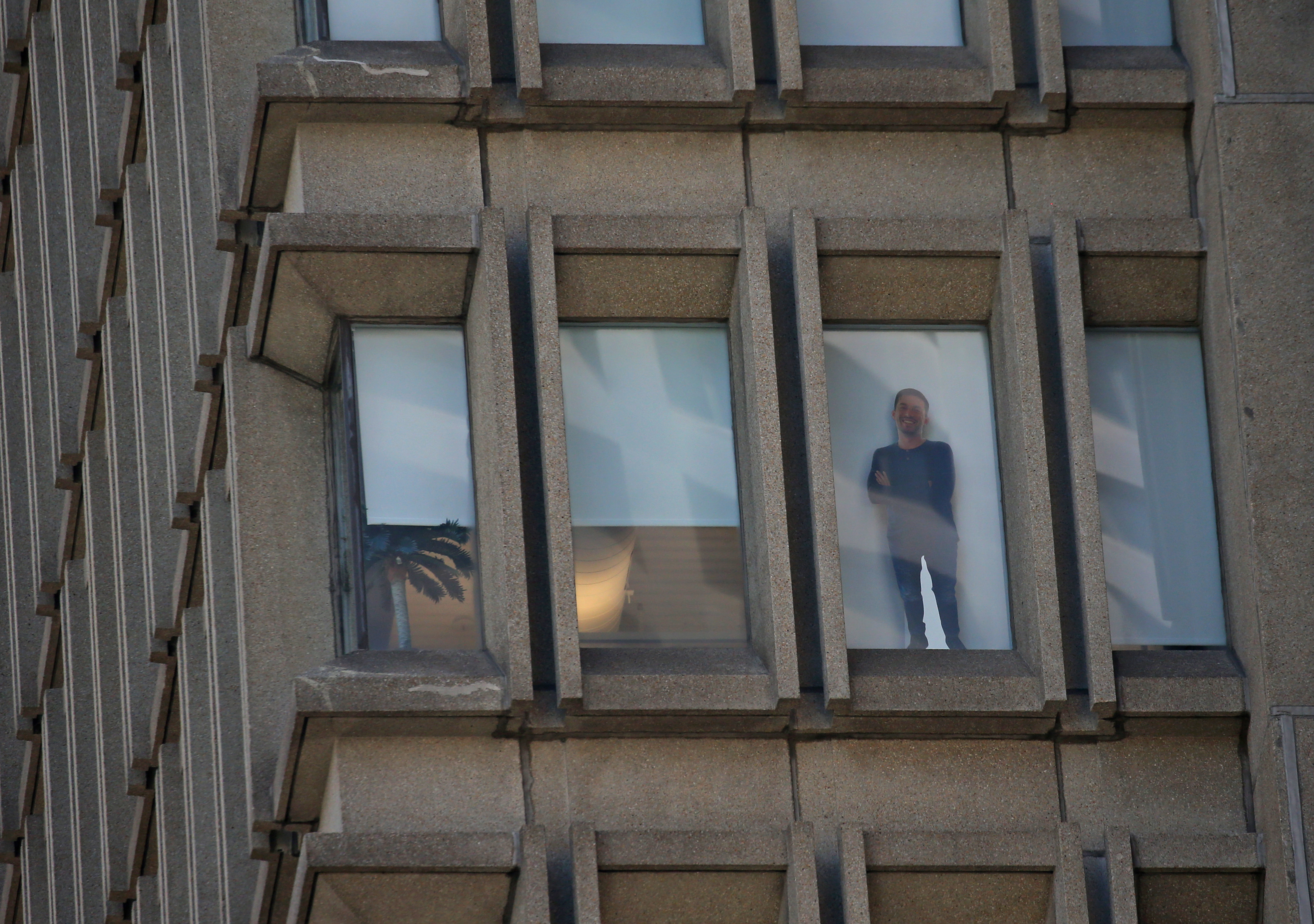 A cardboard cutout of a person stood on a window several stories up at 225 Franklin Street office building in Boston financial district.