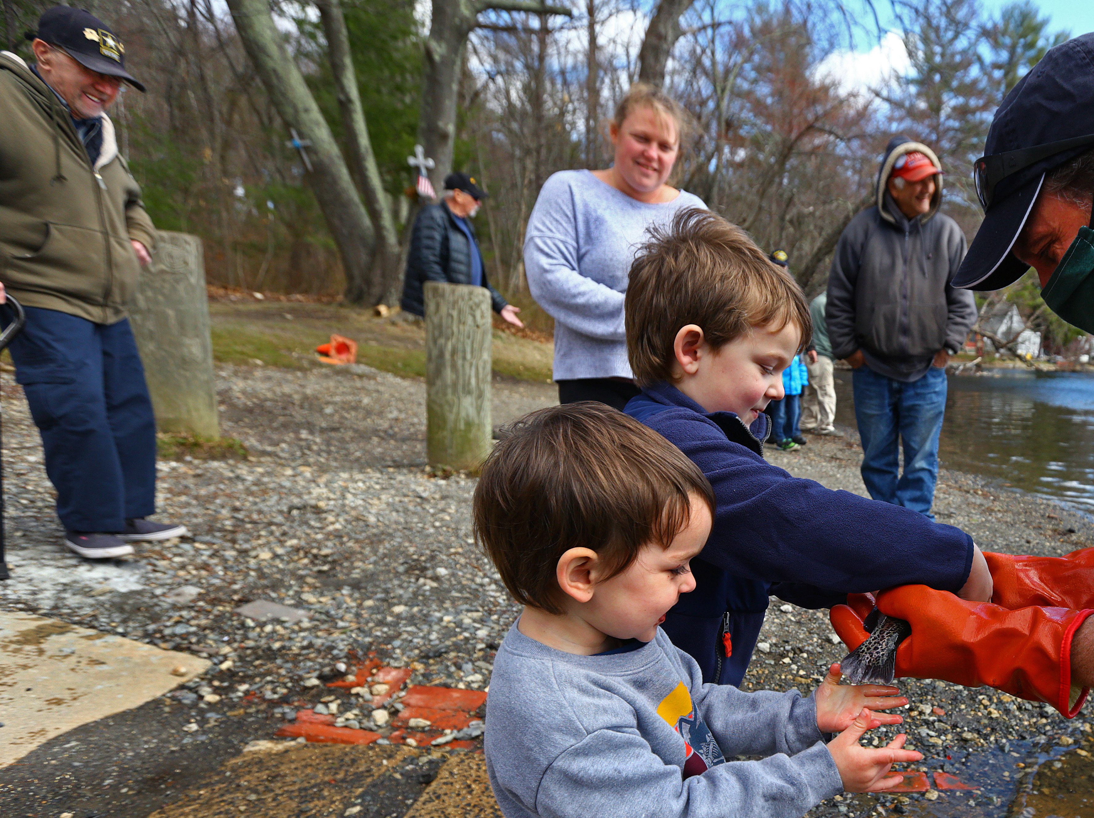 North East District Fisheries manager John Sheedy plucked a fish from the lake and showed it to 3-year-old Lincoln Forrester and his 5-year-old brother, Wyatt.