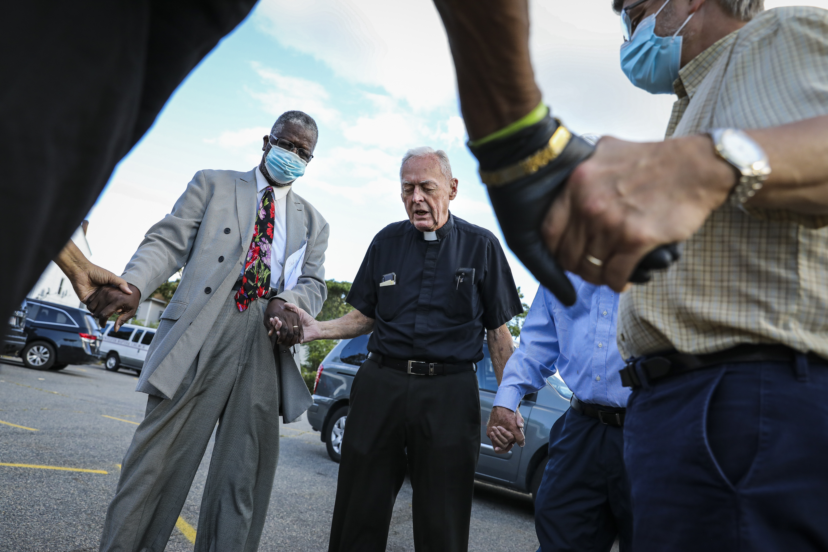 The Rev. Vernard Coulter (left) and the Rev. Richard Conway of St. Mark and St. Ambrose held hands in prayer before their weekly peace walk.