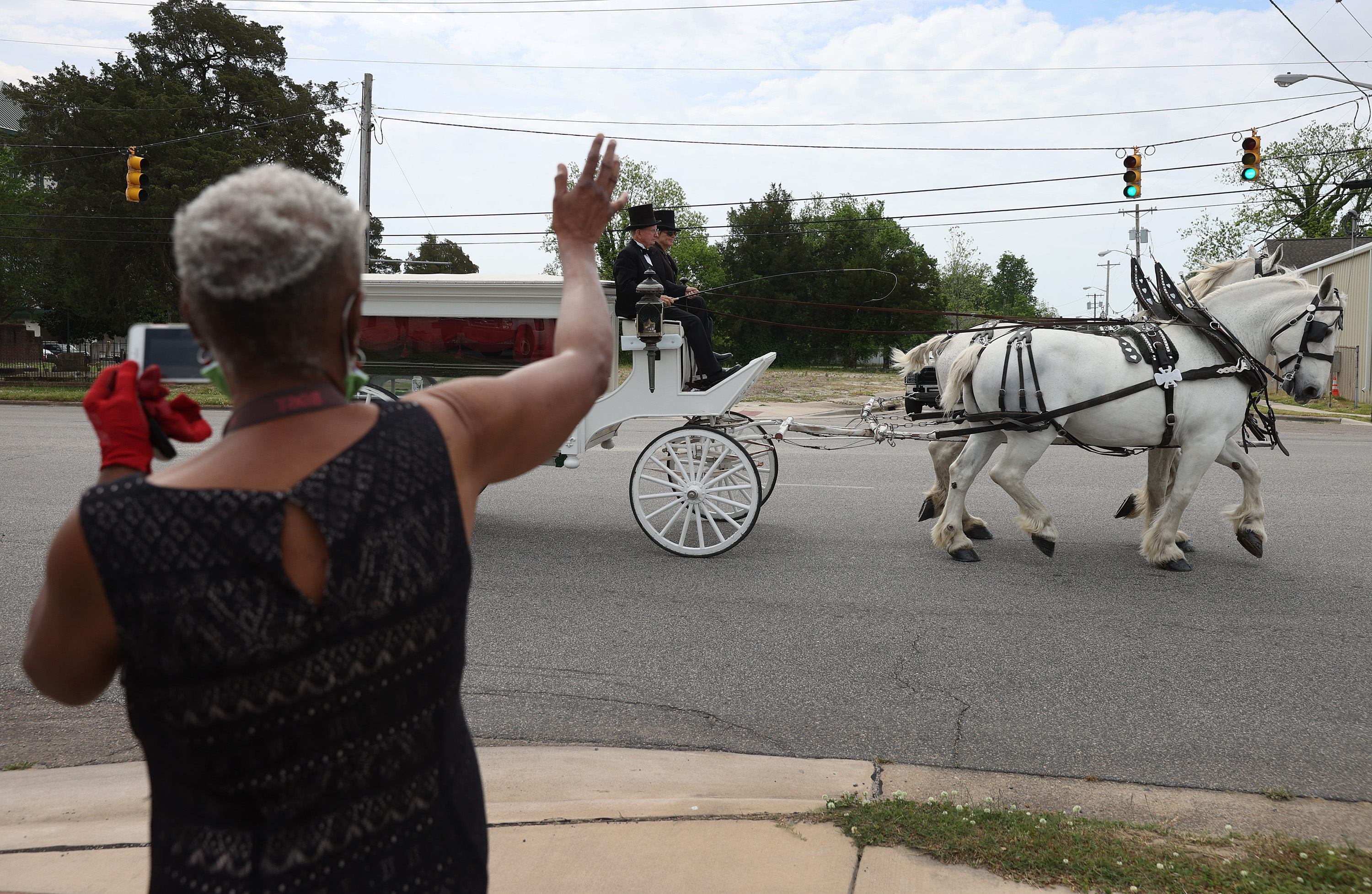 A person waved as a horse drawn carriage drove past with the remains of Andrew Brown Jr.