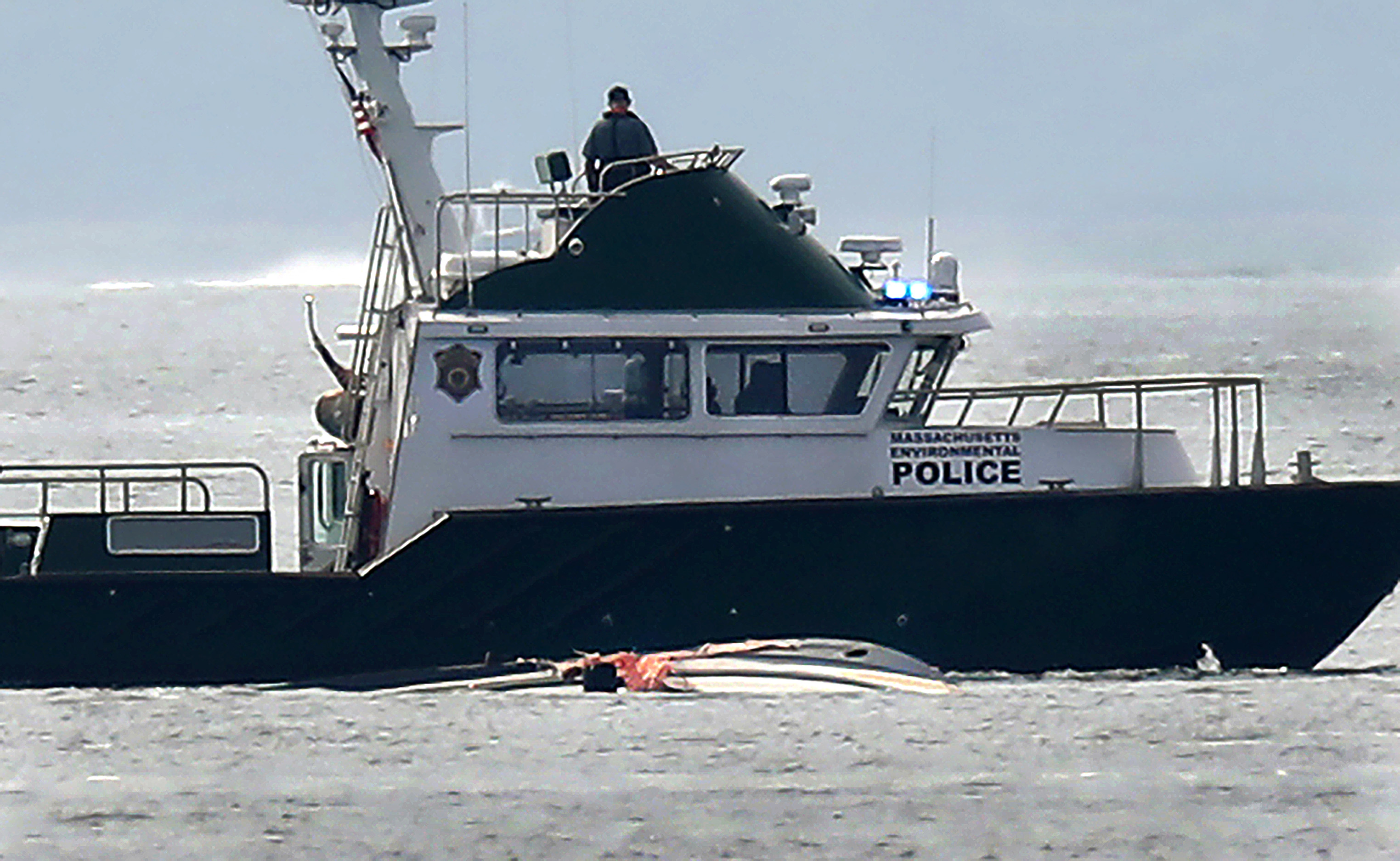 A police boat was positioned by the wreckage of an overturned pleasure boat as the search was underway Saturday morning.