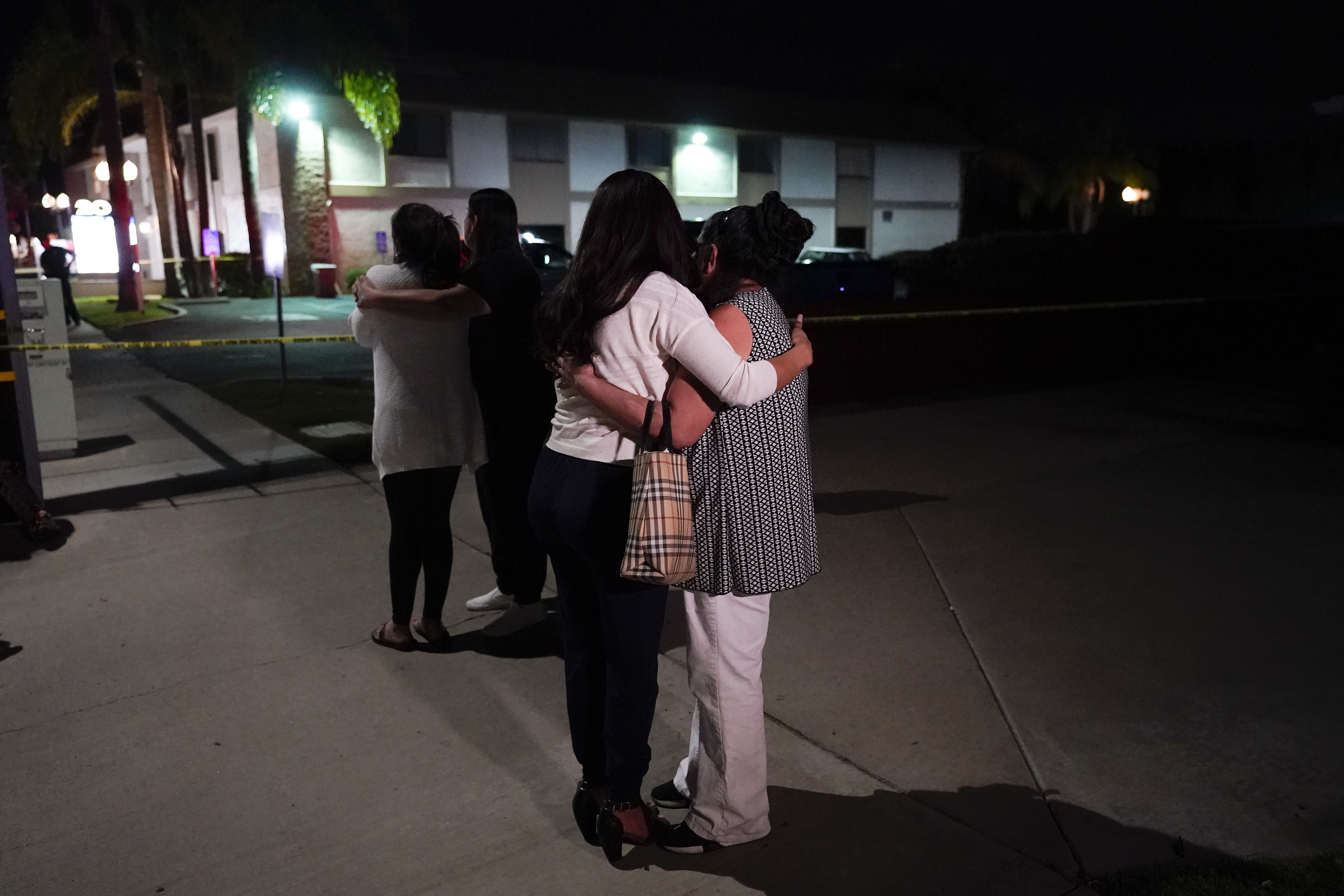 Unidentified people comforted each other as they stood near a business building where a shooting occurred in Orange, Calif.