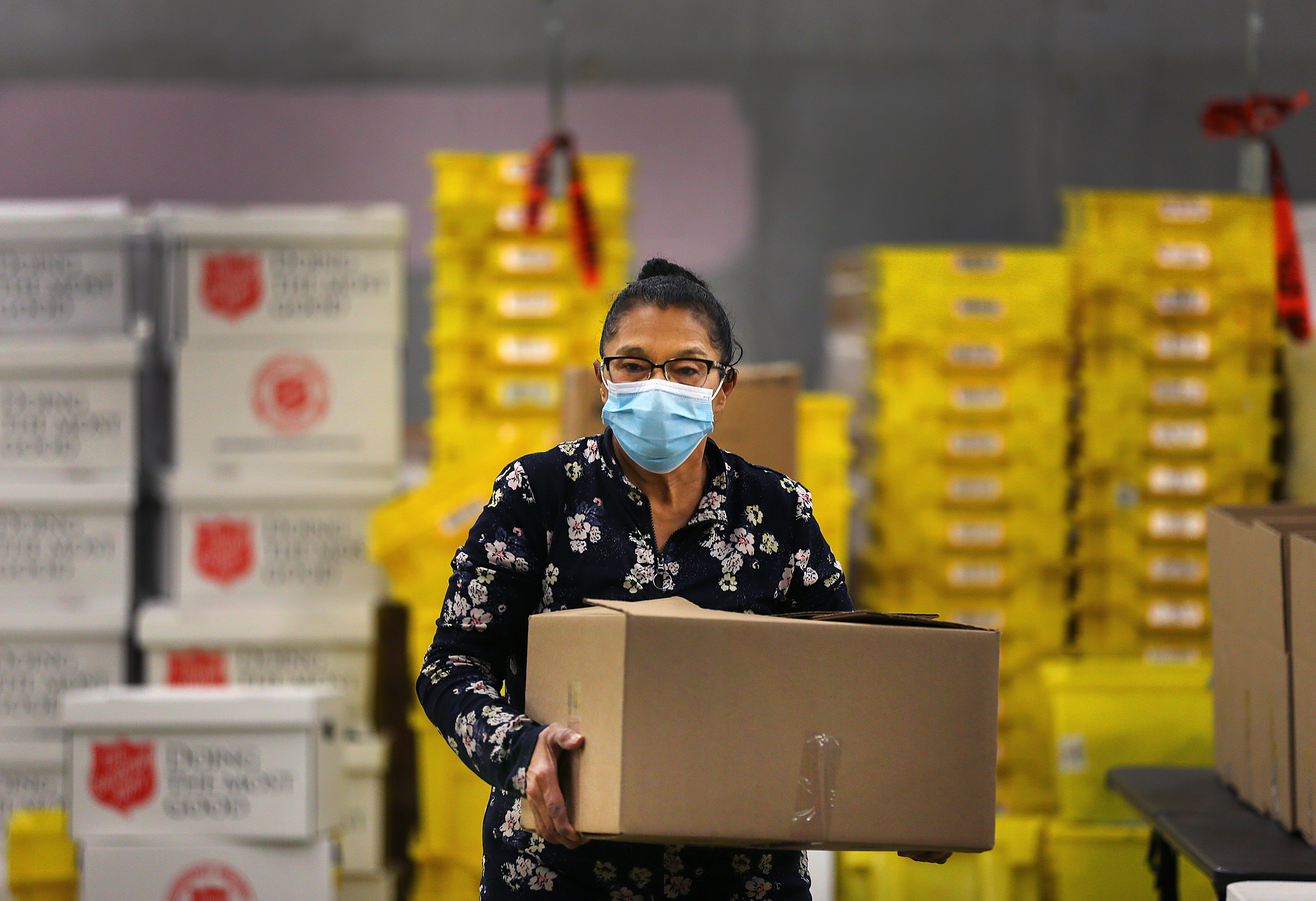 Milagro "Millie" Rodriquez, 64, carries a box as she helps pack food and supplies for COVID-19 patients at the Elisha Project's Pawtucket warehouse.
