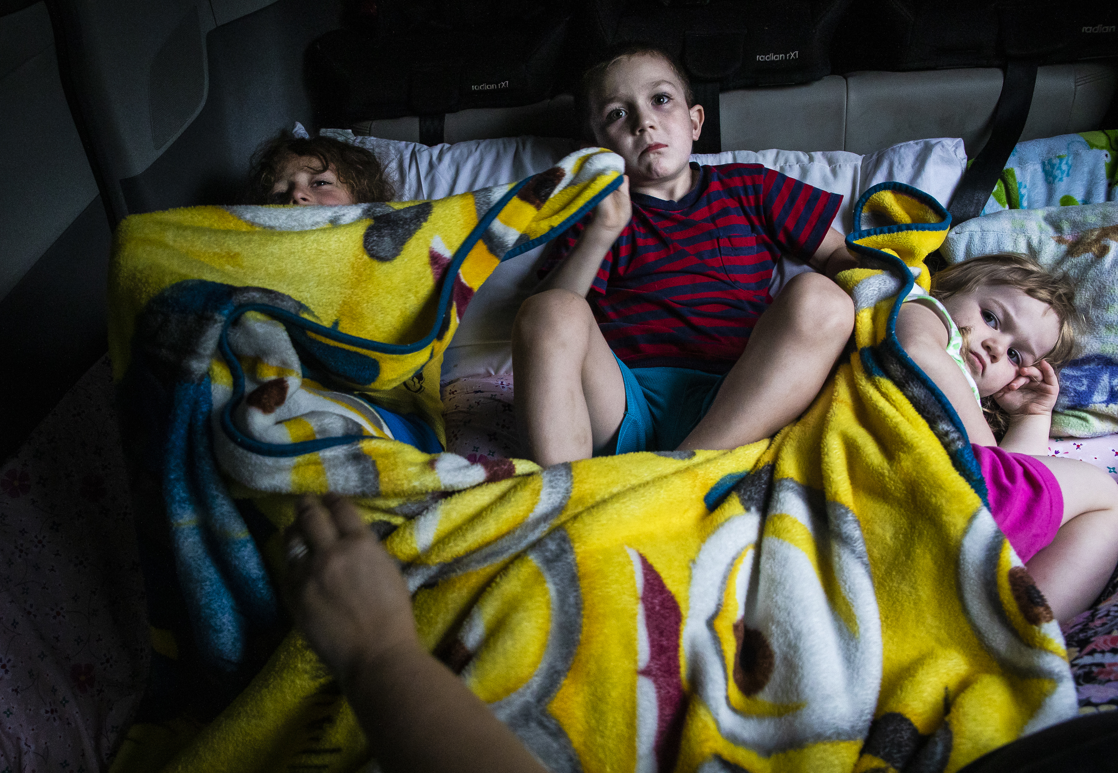 Evan, 7, Dylan, 6, and Laya, 3, watched a movie while getting ready for bed in the back of their family’s van in Biddeford, Maine. The family had been evicted from their three-bedroom apartment earlier that day.