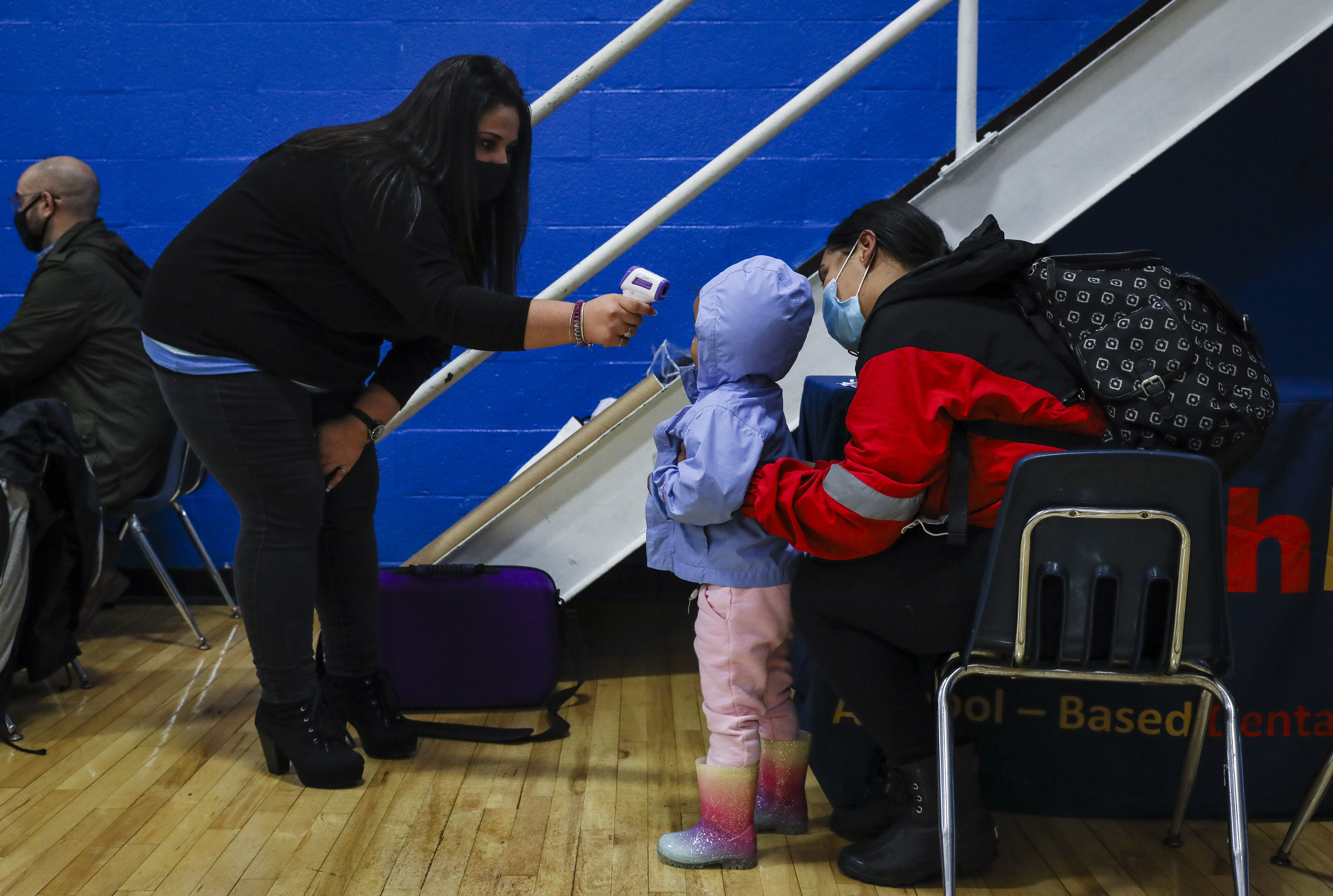 ForsythKids business manager Mandy Sadri took the temperature of 2-year-old Emma Alvarez while her mom, Grace Duran, comforted her from behind.