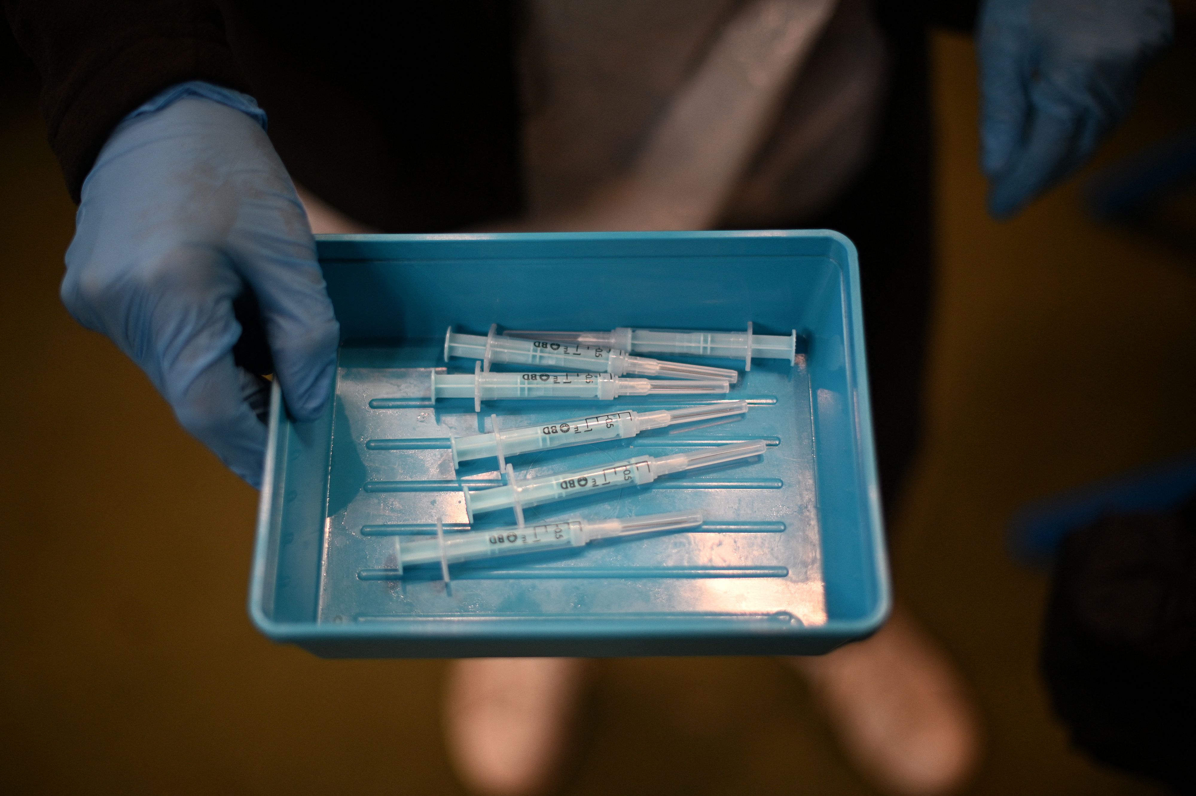 A clinician displayed a tray of syringes filled with prepared doses of a Moderna Covid-19 booster vaccine.