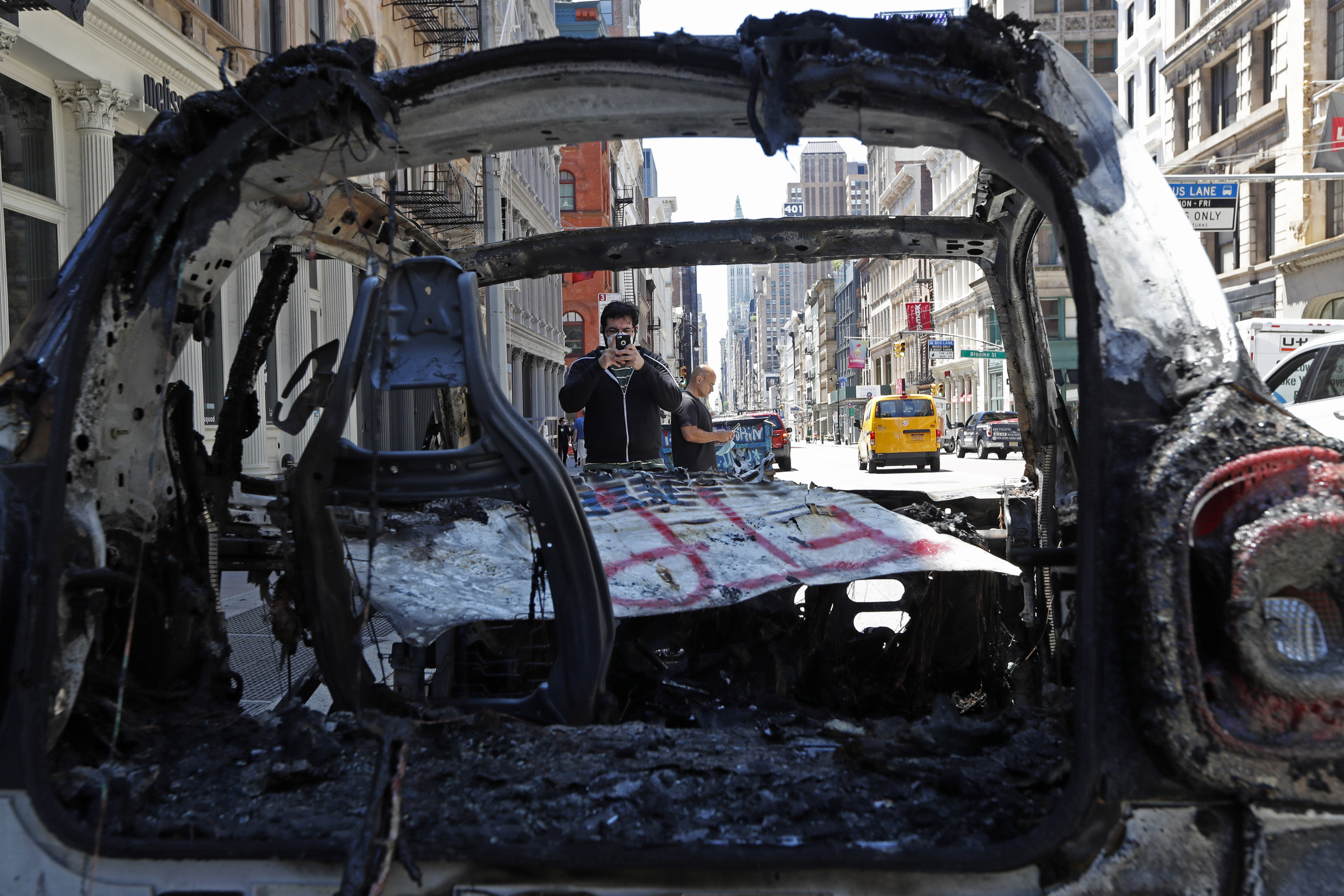 A man stopped to take a photo of a burned out New York City police vehicle on Sunday along Broadway in Lower Manhattan.