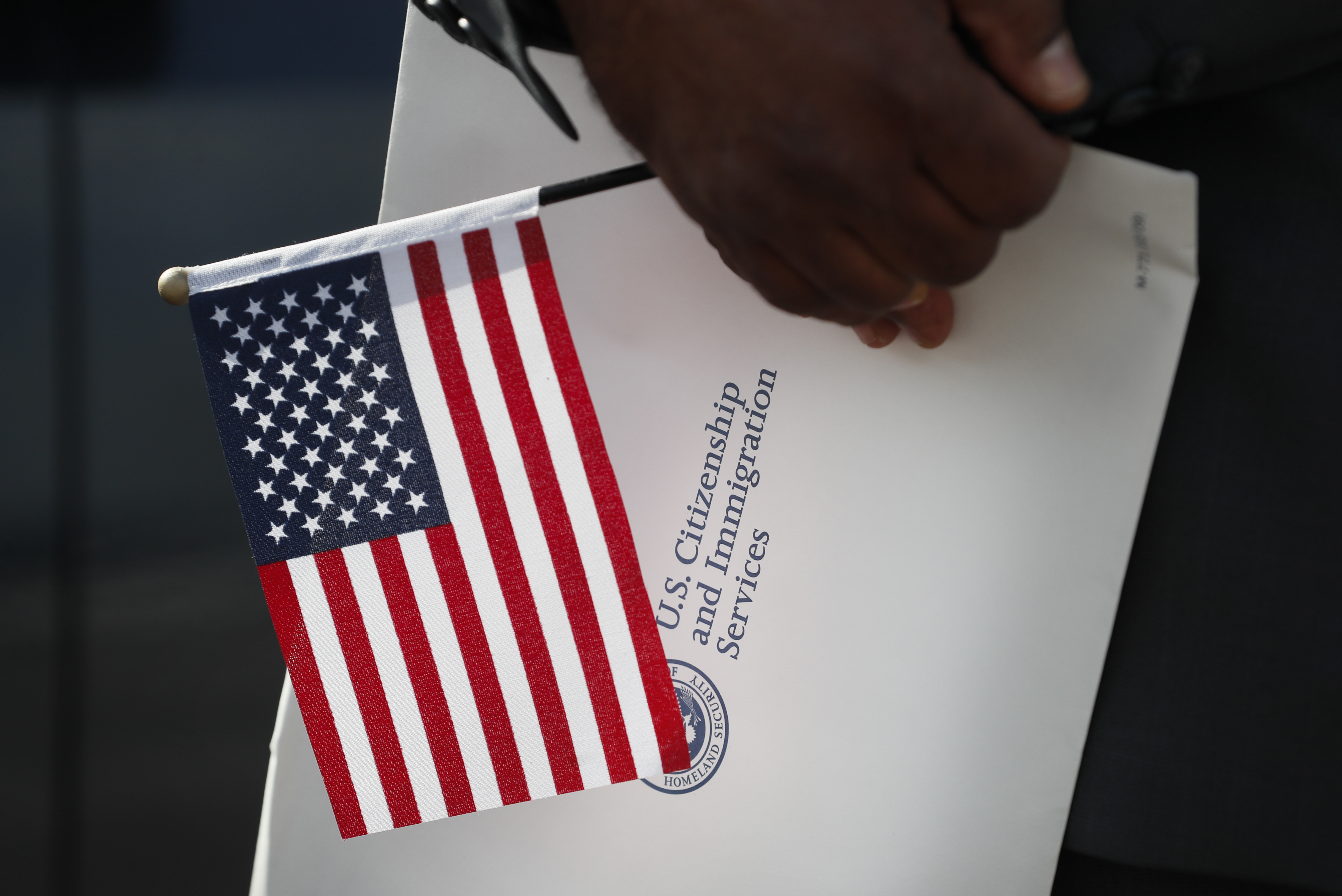 Maweya Babekir, of Iowa City, Iowa, holds a flag before taking the Oath of Allegiance during a drive-thru naturalization ceremony at Principal Park, Friday, June 26, 2020, in Des Moines, Iowa.