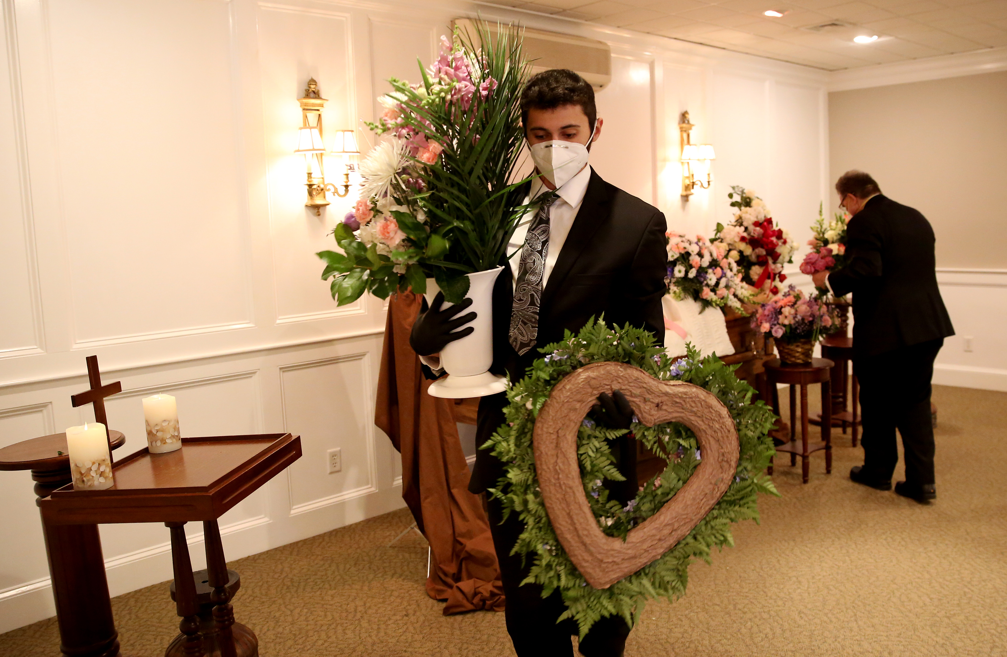 Matt Tauro carried flowers that adorned the casket to the limo so that they could be brought to the cemetery for a graveside service being held for a woman who died of coronavirus.