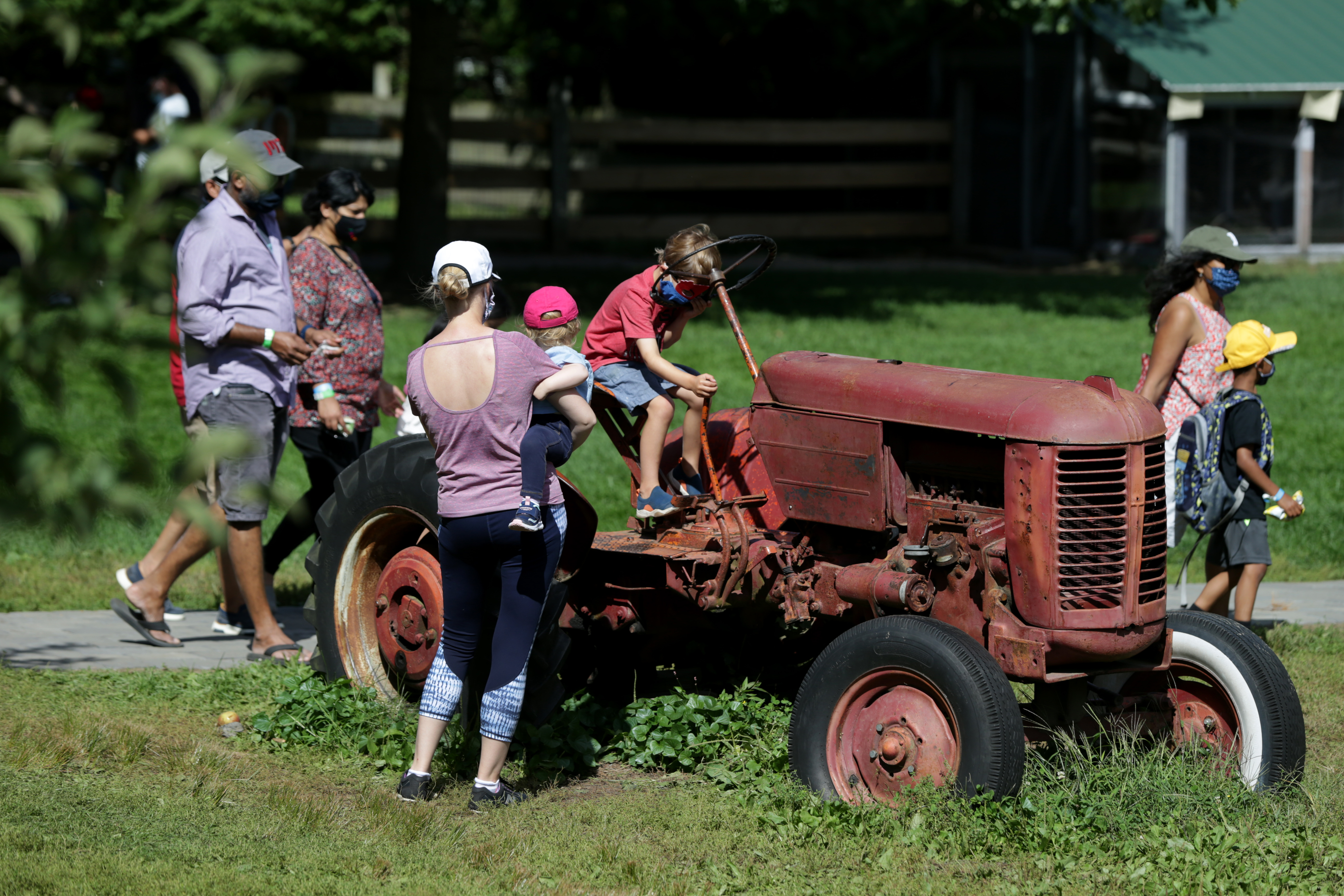 Kids climb on an old tractor at Honey Pot Hill Orchards in Stow, which has installed handwashing stations at entrances to the apple-picking areas.