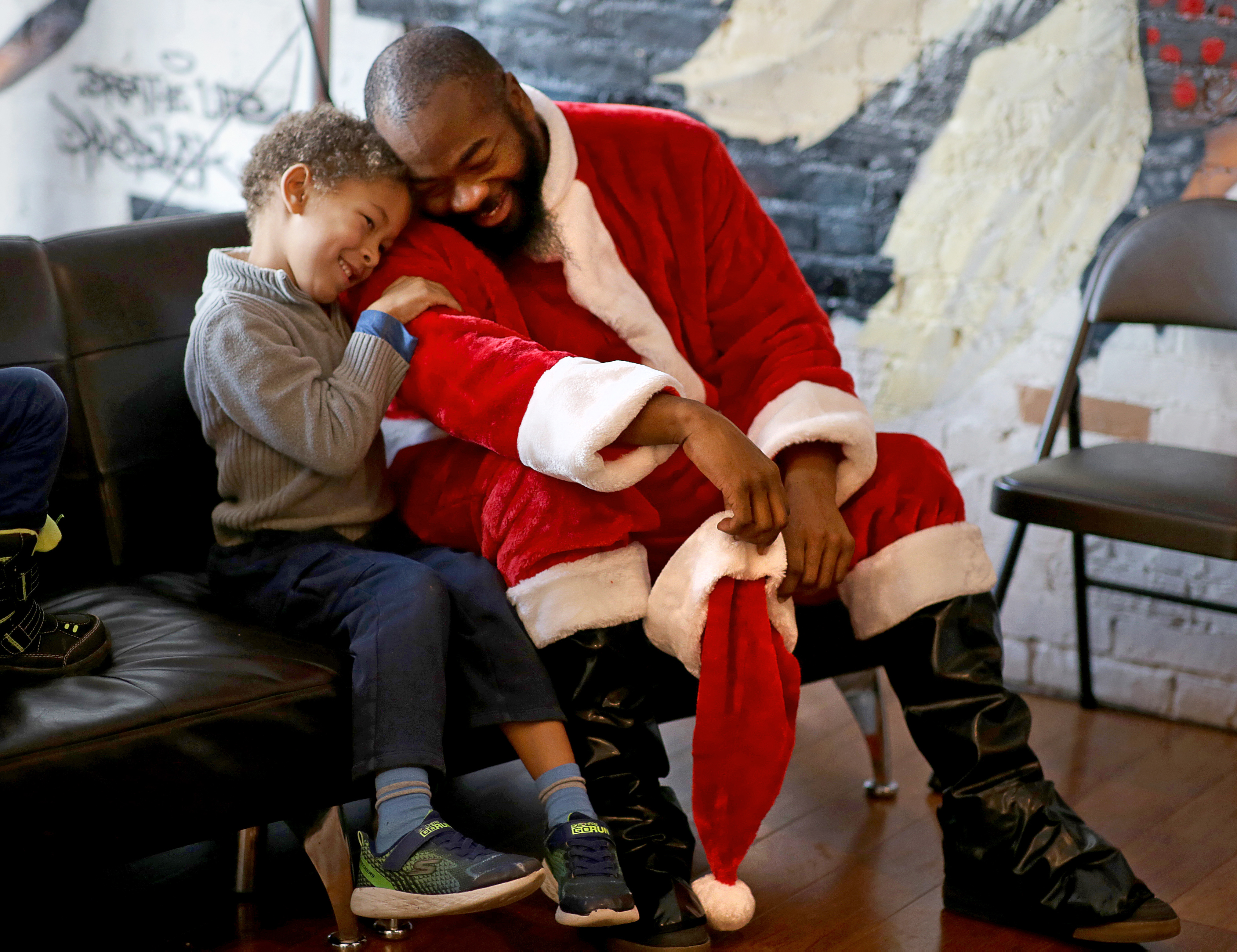 Isaac Holbert (left) enjoyed the company of Santa Claus, portrayed by Eddie A. Brimage at the Black Market in Boston on Dec. 7.