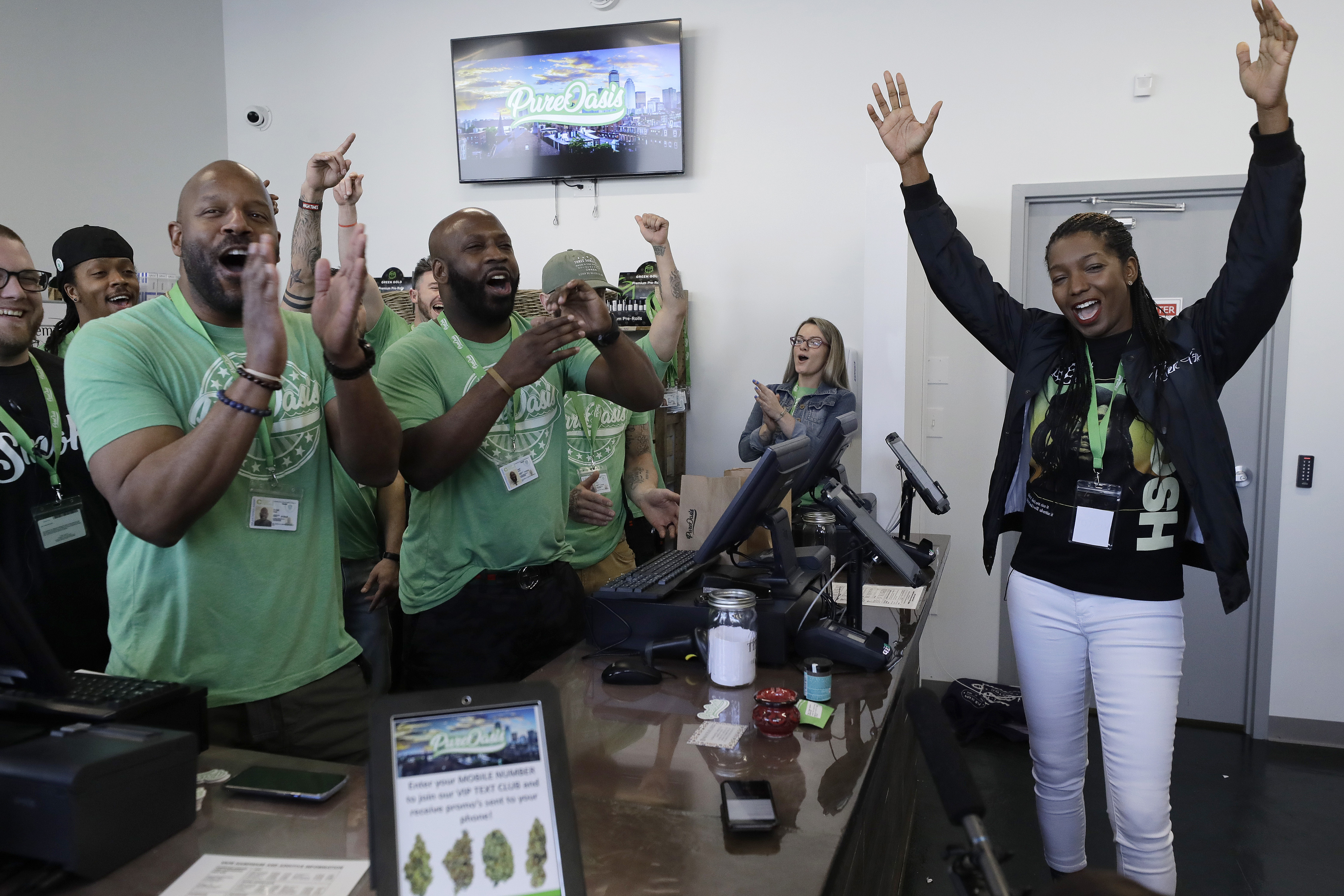 Entrepreneurs Kobie Evans (front left) and Kevin Hart (center left) celebrated the opening of the Pure Oasis recreational marijuana shop with their first customer, Niambe McIntosh (right). The store opened in Boston’s Grove Hall neighborhood on March 9, 2020, becoming the state's first operational Black-owned cannabis company.