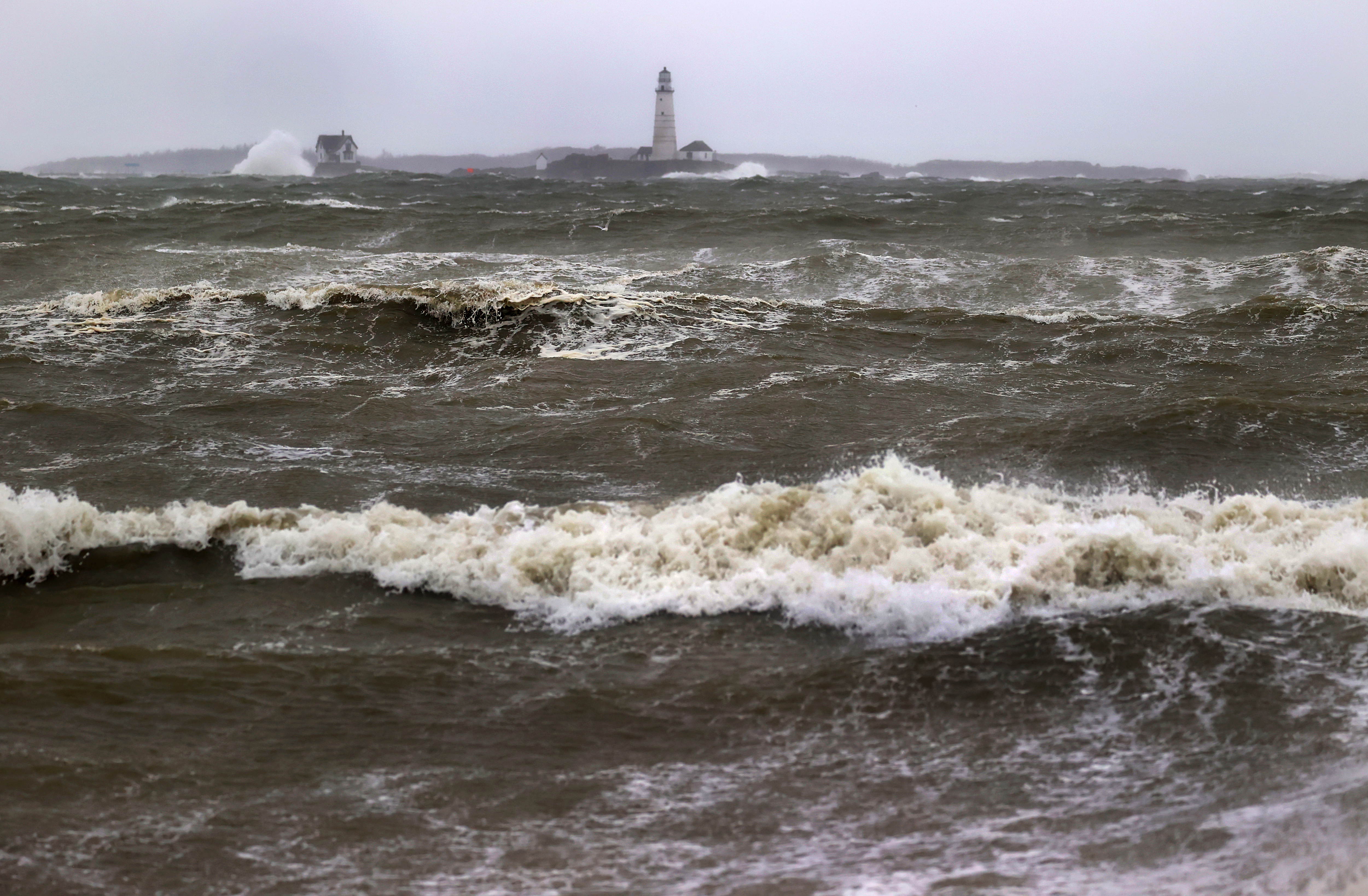 Rough seas surround Boston Light and hit the Hull shore during the storm.