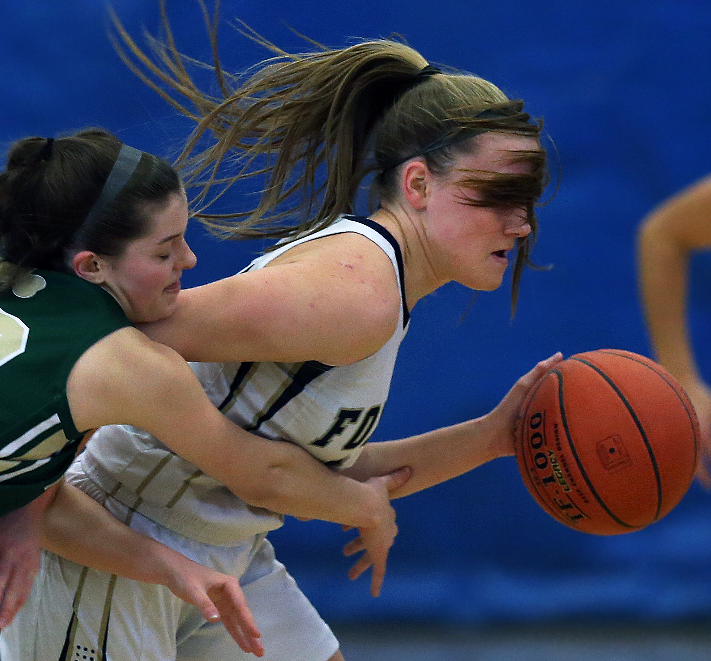 Foxborough’s Lizzy Davis (right) had her view temporarily blocked by her own hair as she pushed the ball up court with Bishop Feehan’s Amanda Folan (left) defending during a game January 19.