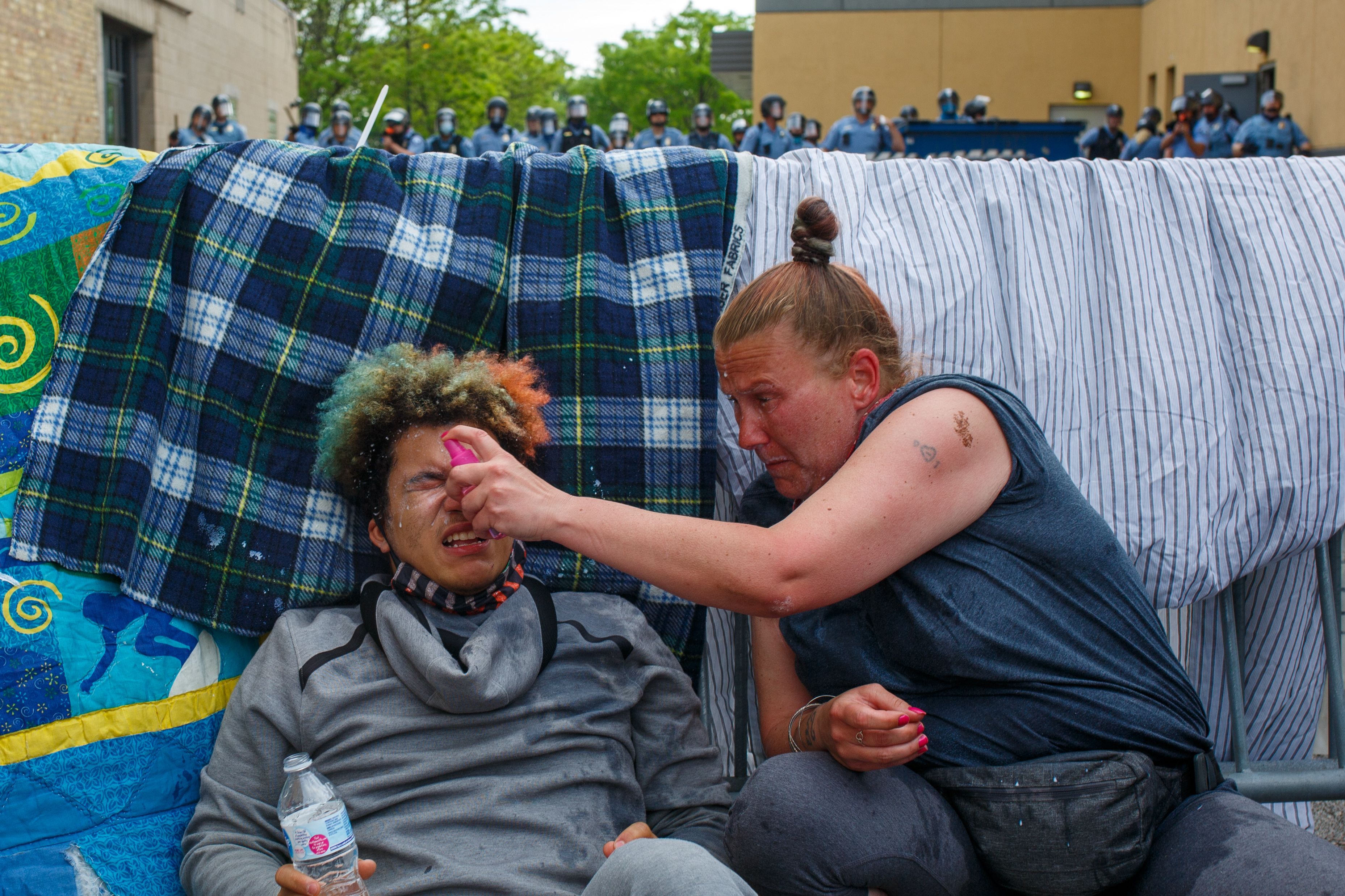 A woman helped clean a man's eye from tear gas.