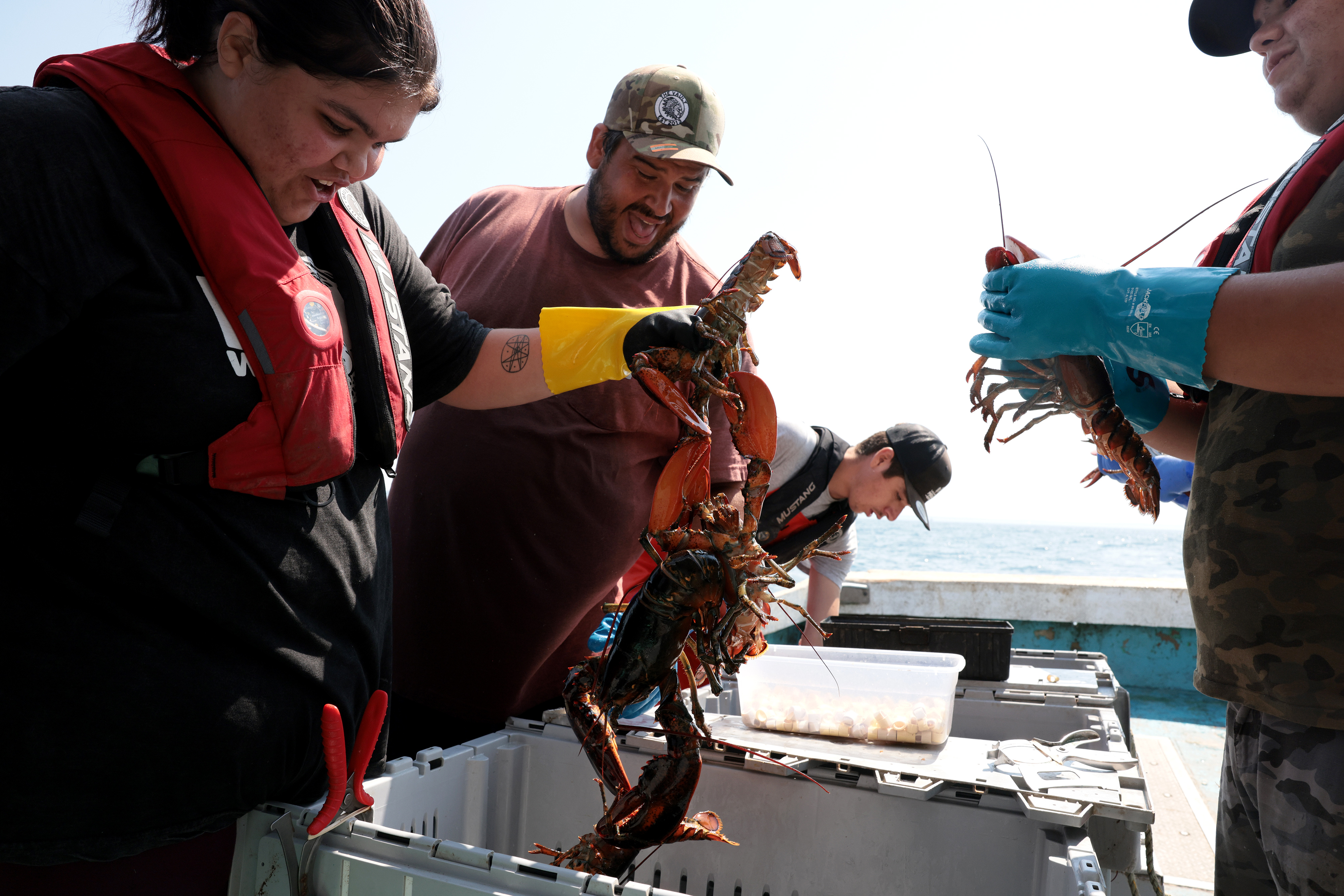 Kaleah Sack, 18, (left) laughed as she pulled up a clump of lobsters with her uncle, James Nevin, (right) beside her, as they checked their treaty traps off Saulnierville, Nova Scotia, on Aug 26. On each of the traps, a special green tag identified them as belonging to his band of the Mi’kmaw people, who insist that a 269-year-old treaty grants them the right to fish when and how they want. But the Canadian government has rejected their assertions, and fisheries officials have been seizing their traps.
