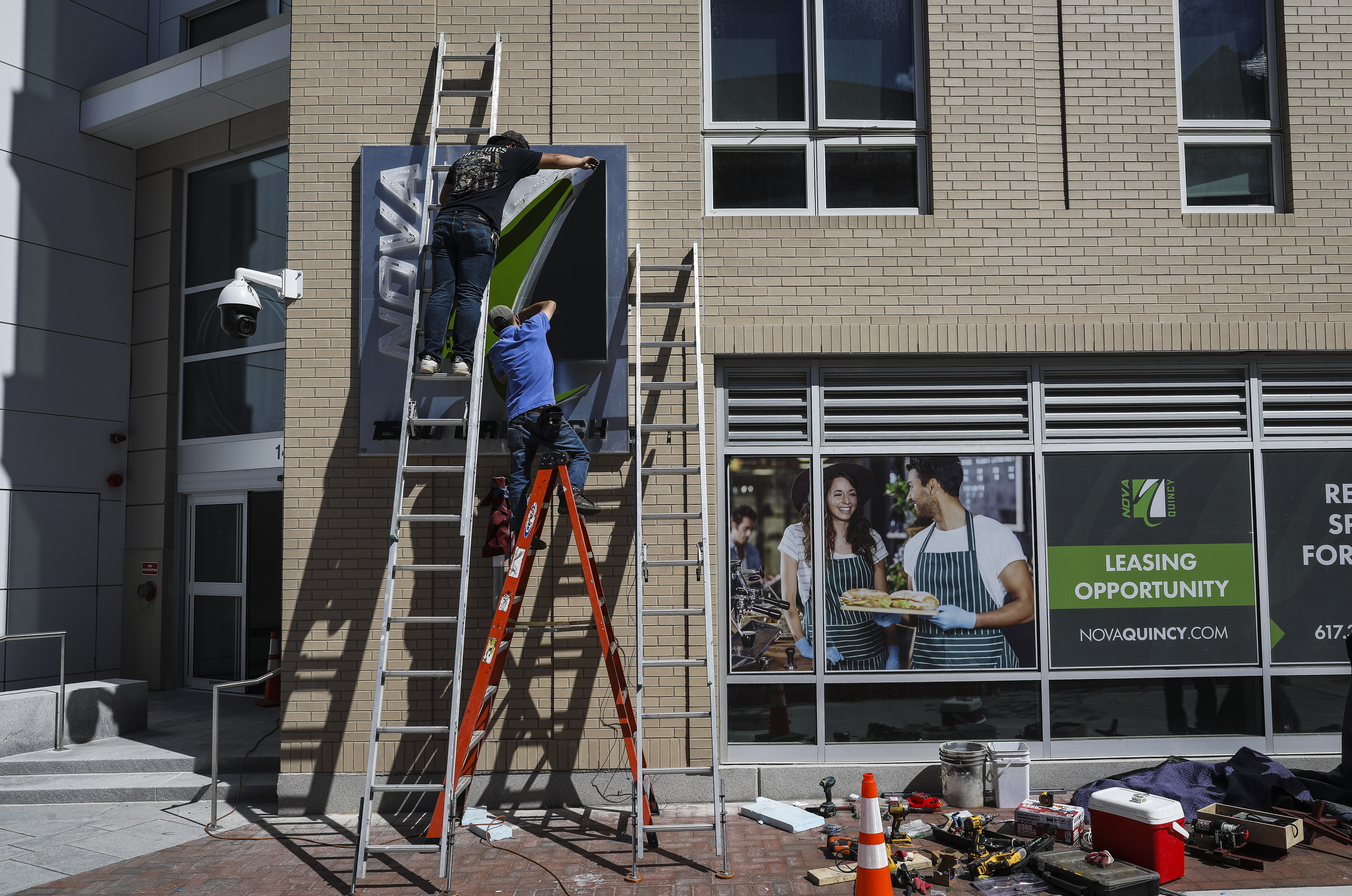 Men work on the exterior of a new building on Hancock Street in Quincy Center.