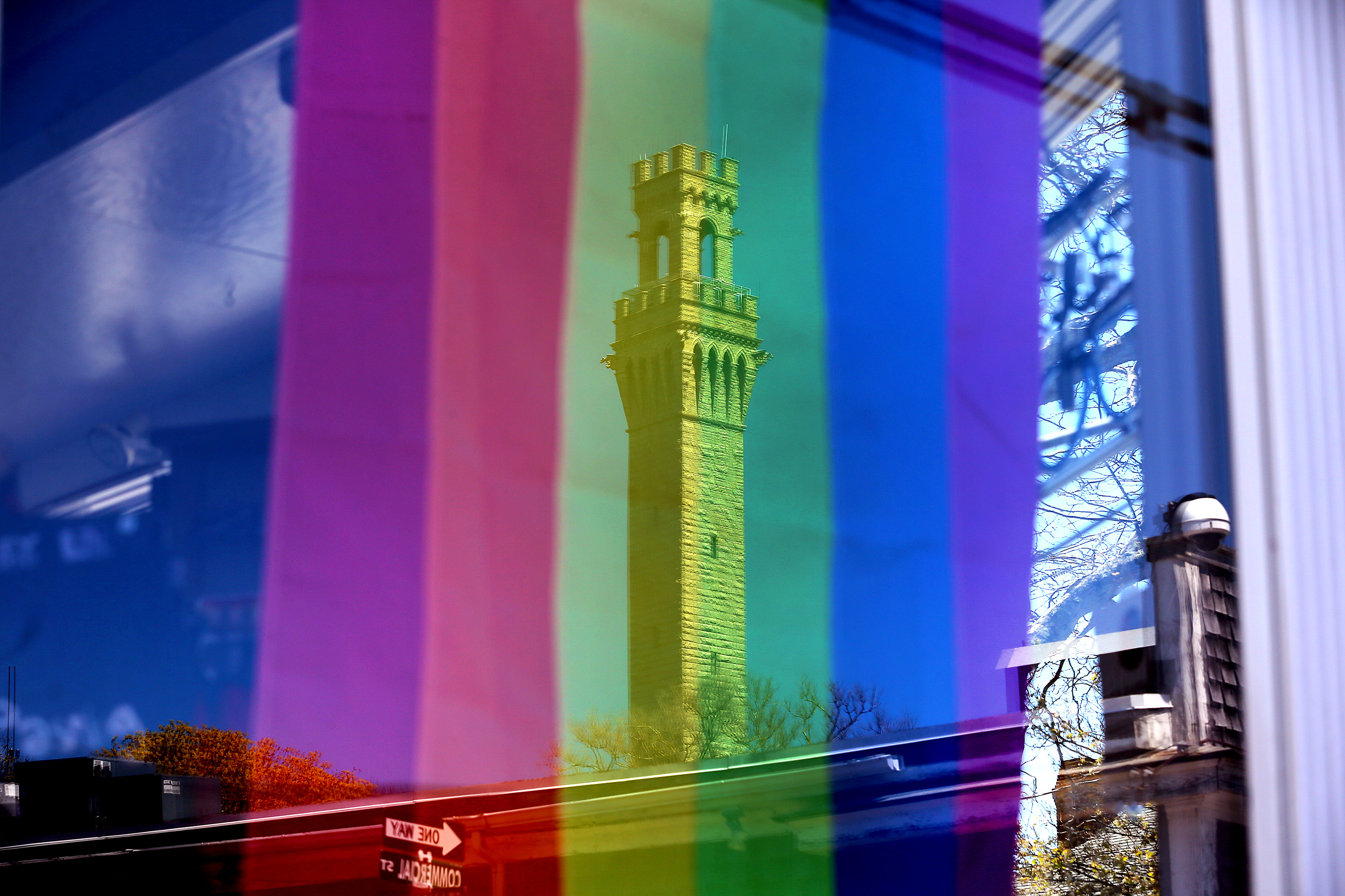 A rainbow flag was displayed in a Commercial Street business where a window reflected the Pilgrim Monument.