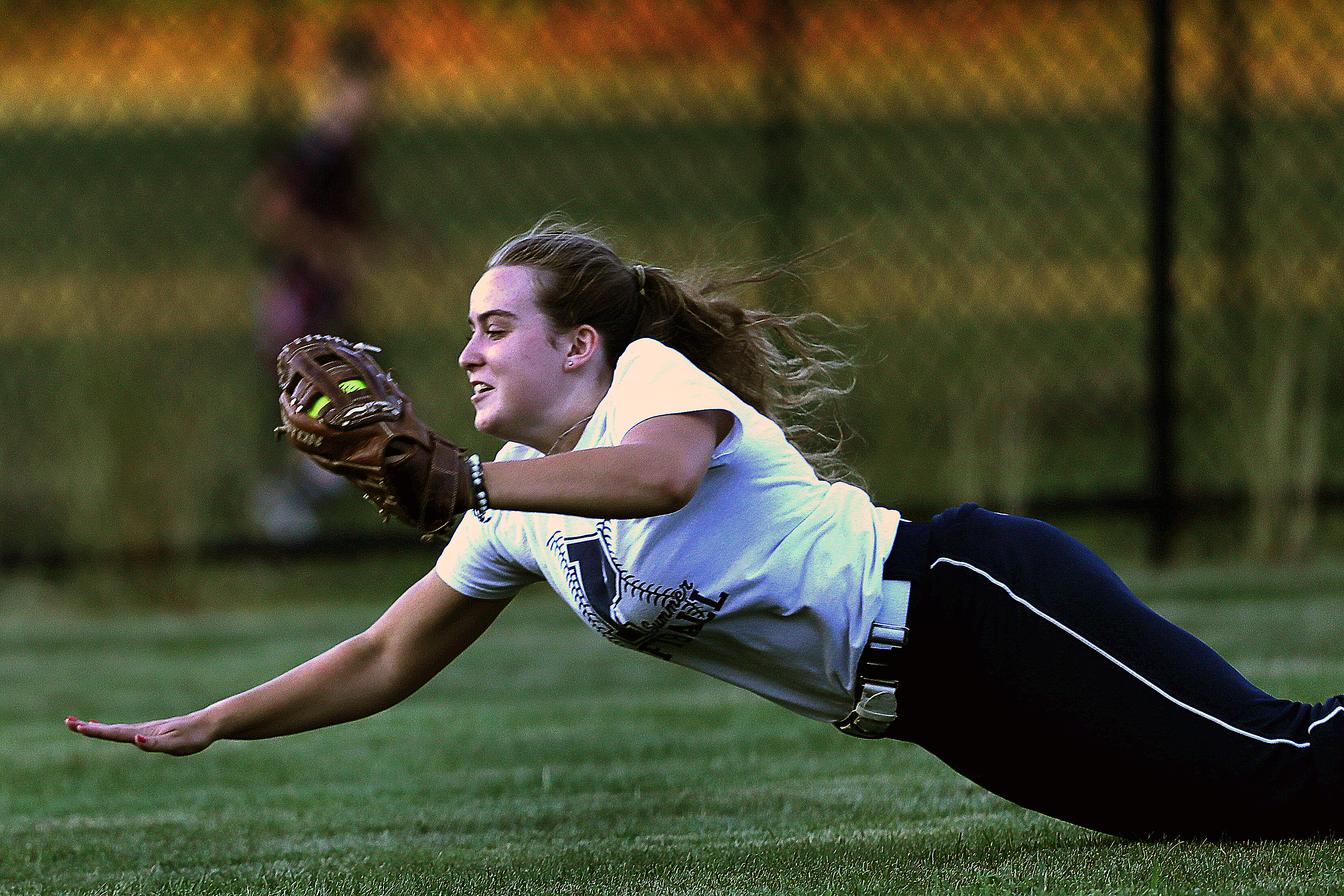 . . . fully extending her body and bracing for the landing on the outfield grass . . .