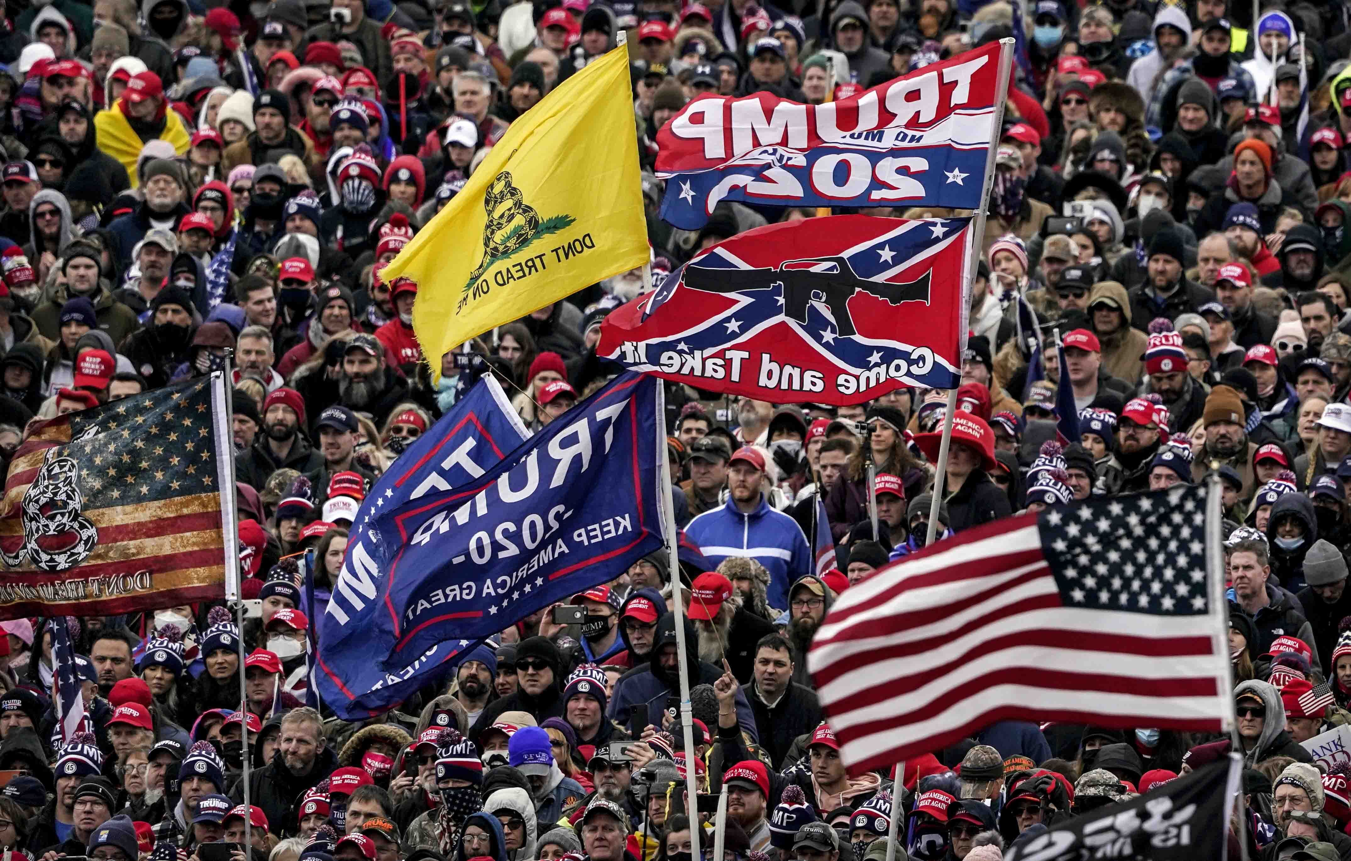 Supporters of President Donald Trump, with a Confederate-themed flag among others, listen to him speak as they rally in Washington before the deadly Jan. 6 insurrection at the US Capitol.