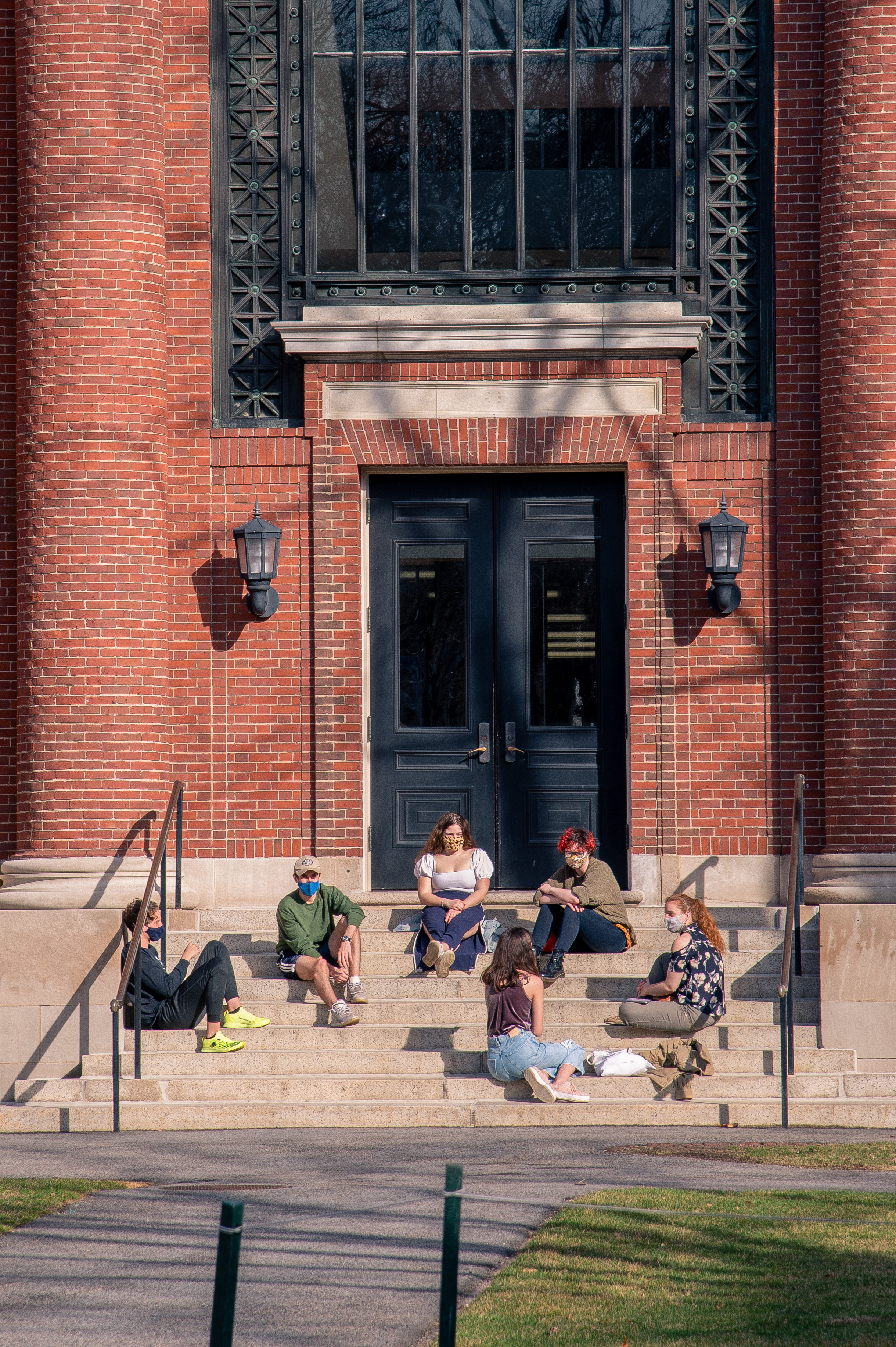 Students gather, while giving one another distance, on the stairs of Emerson Hall at Harvard University.