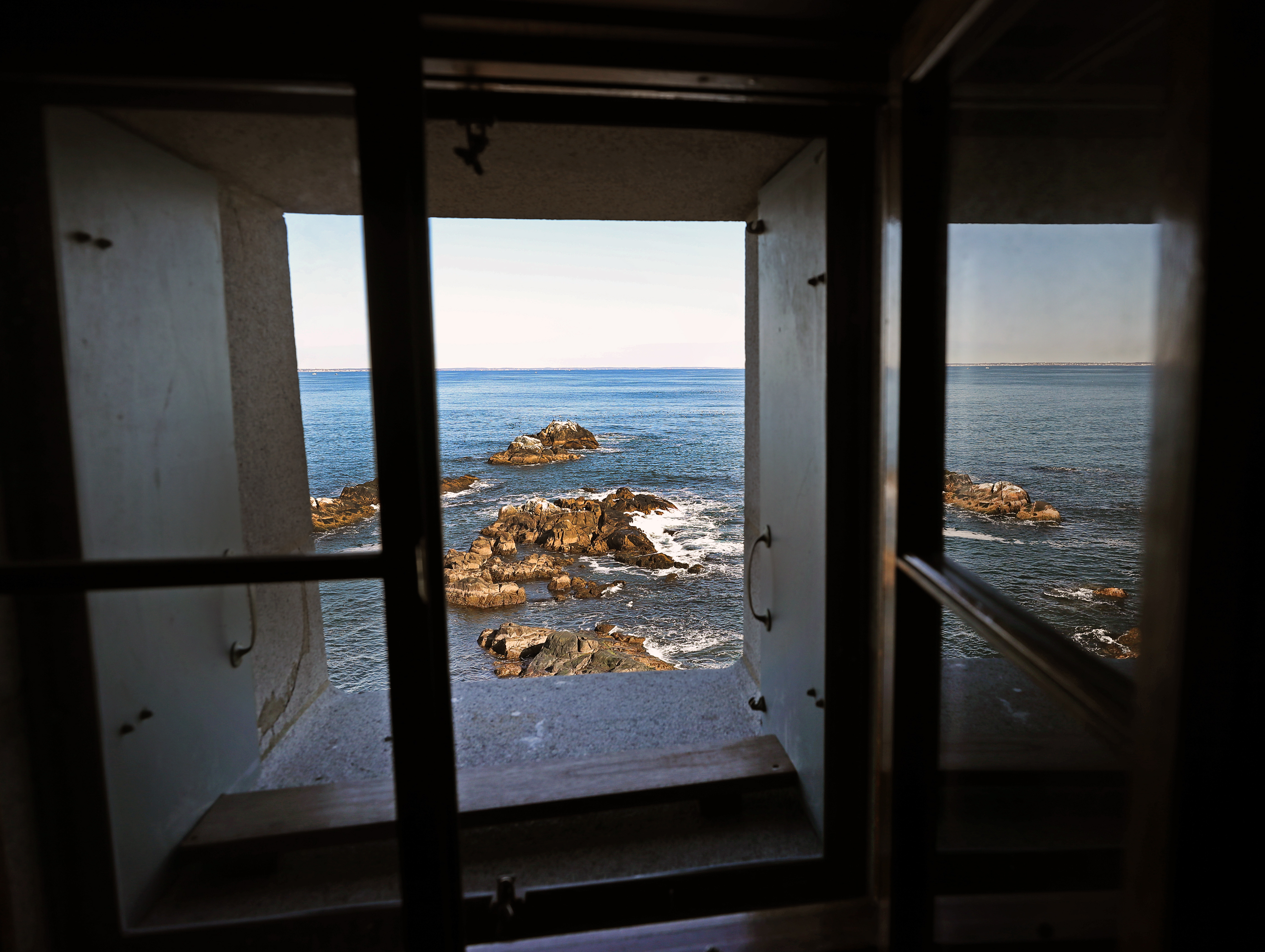 A window view from Graves Light overlooking rocks below.