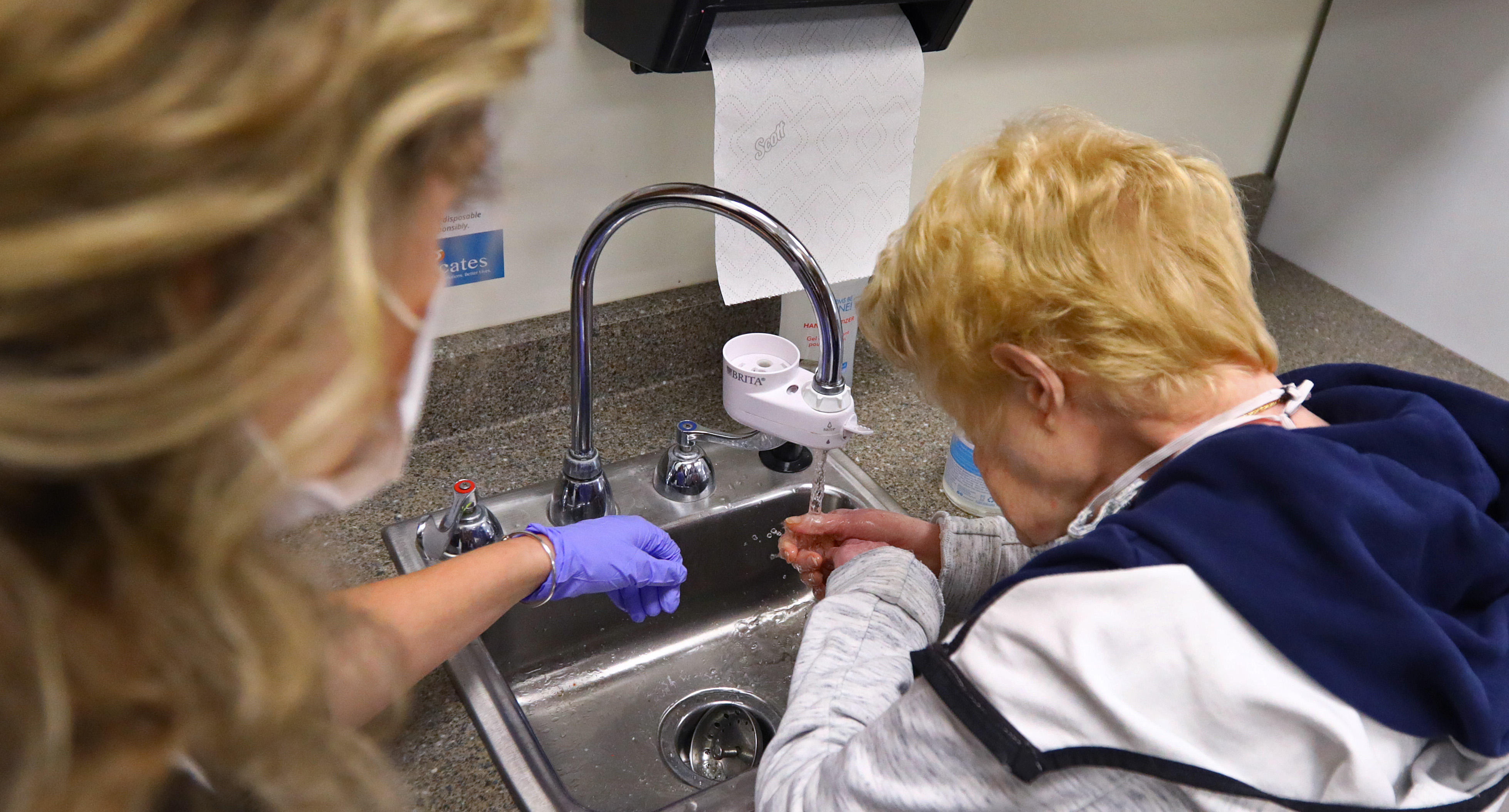 Senior health care coordinator Emily Donahue helped participant Marylou Watson with washing her hands in the day habilitation room at Advocates Day Services.