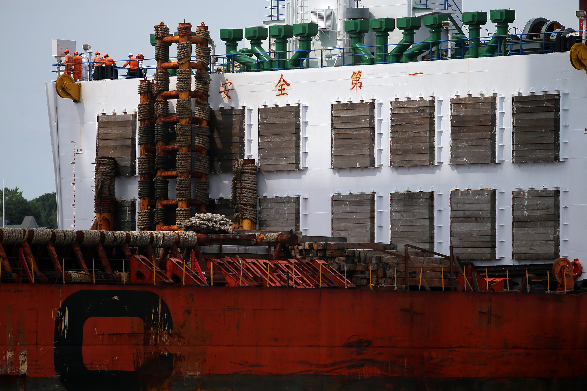 Crew members watch as the Zhen Hua 15 docks at the Paul W. Conley Container Terminal in Boston Harbor. The Chinese characters seen on the ship read “an chuan di yi," or “safety first.”
