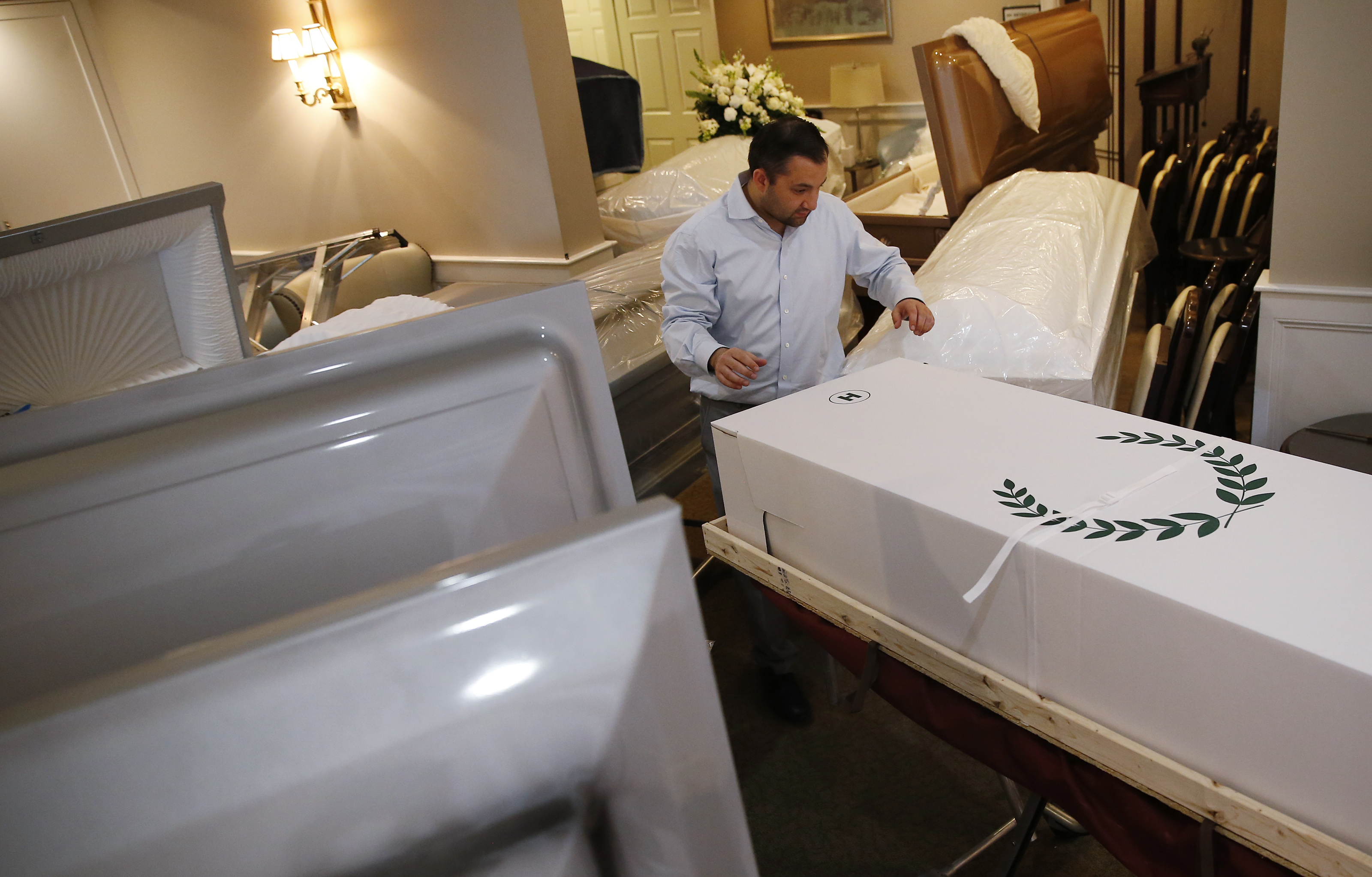 East Boston, MA - 4/28/20: Funeral director Joe Ruggiero, the second generation to run his family's business, moves a body into a makeshift storage area that Ruggiero Family Memorial Home usually uses as a tribute room where photos are displayed and coffee served to families during wakes as funeral homes cope with a coronavirus or COVID-19 surge. (Jessica Rinaldi/Globe Staff)