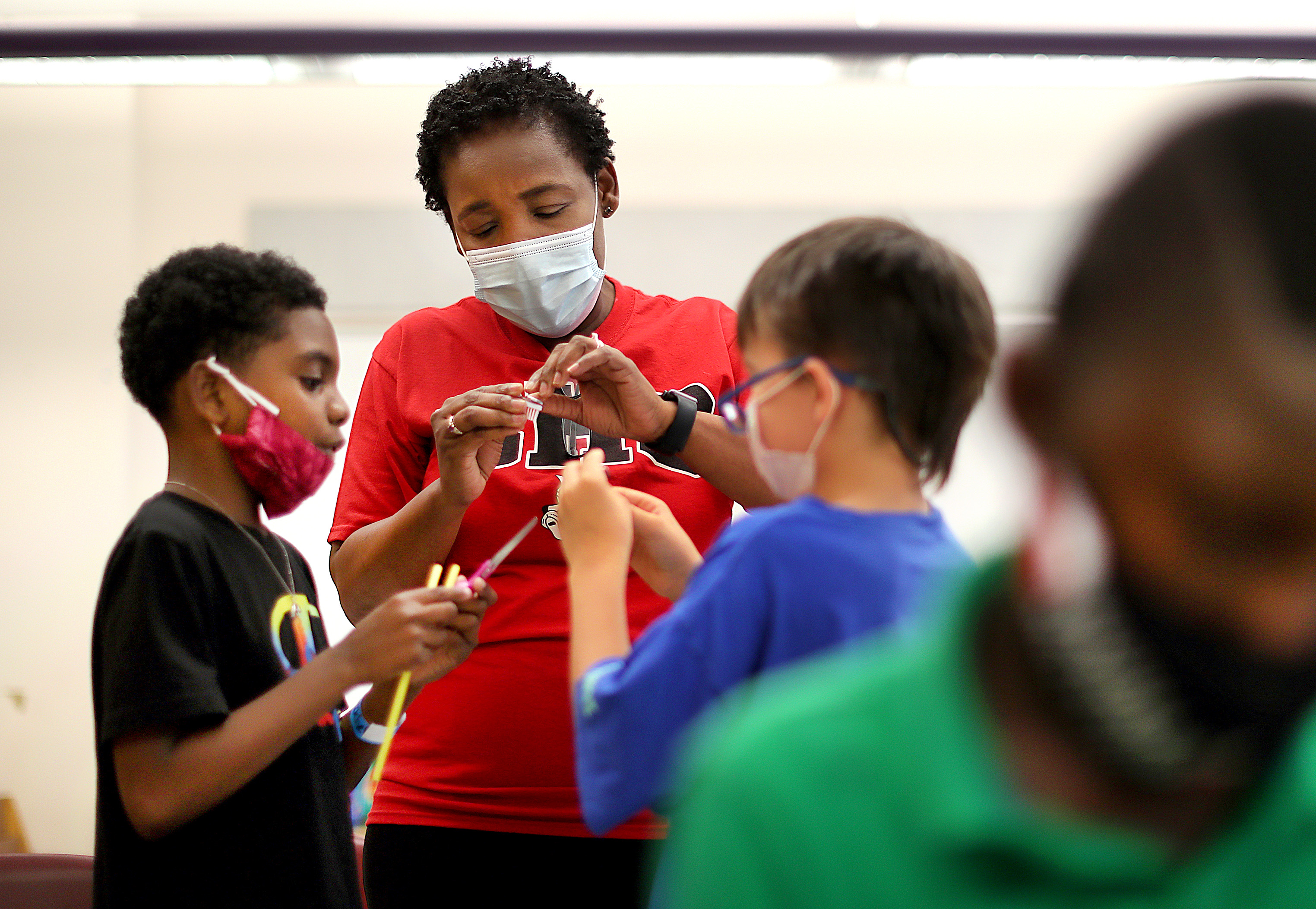 At Brockton's Louis F. Angelo Elementary School, teacher Vena Ulysse helps students Jayve Jackson (left) and Dominic Marshall with their robot pieces, part of a robotics and coding summer program funded through federal relief aid. Brockton schools will also see millions in state aid through the Student Opportunity Act.