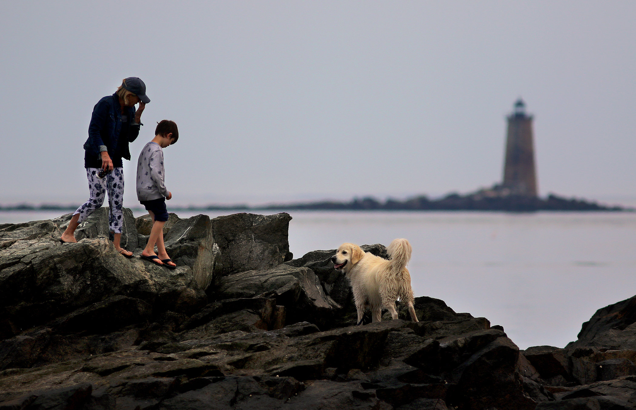 Beachcombers clambered over rocks on New Castle Island with Whaleback Lighthouse in the distance.