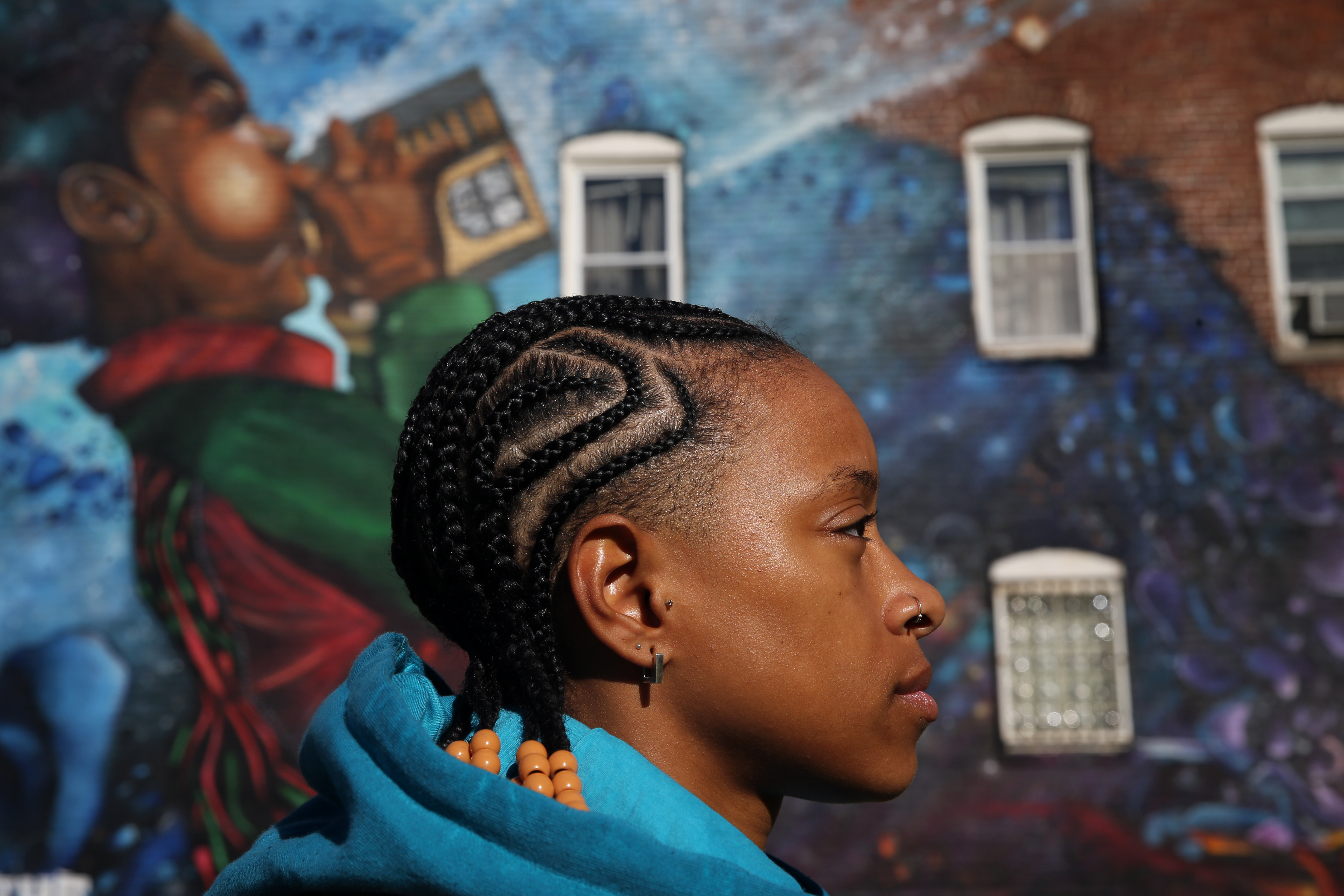 Jet Spratling, artist and founder of @Intersection222 celebrating queer lives, claiming space and joy, in front of the Breathe Life mural by Problak.