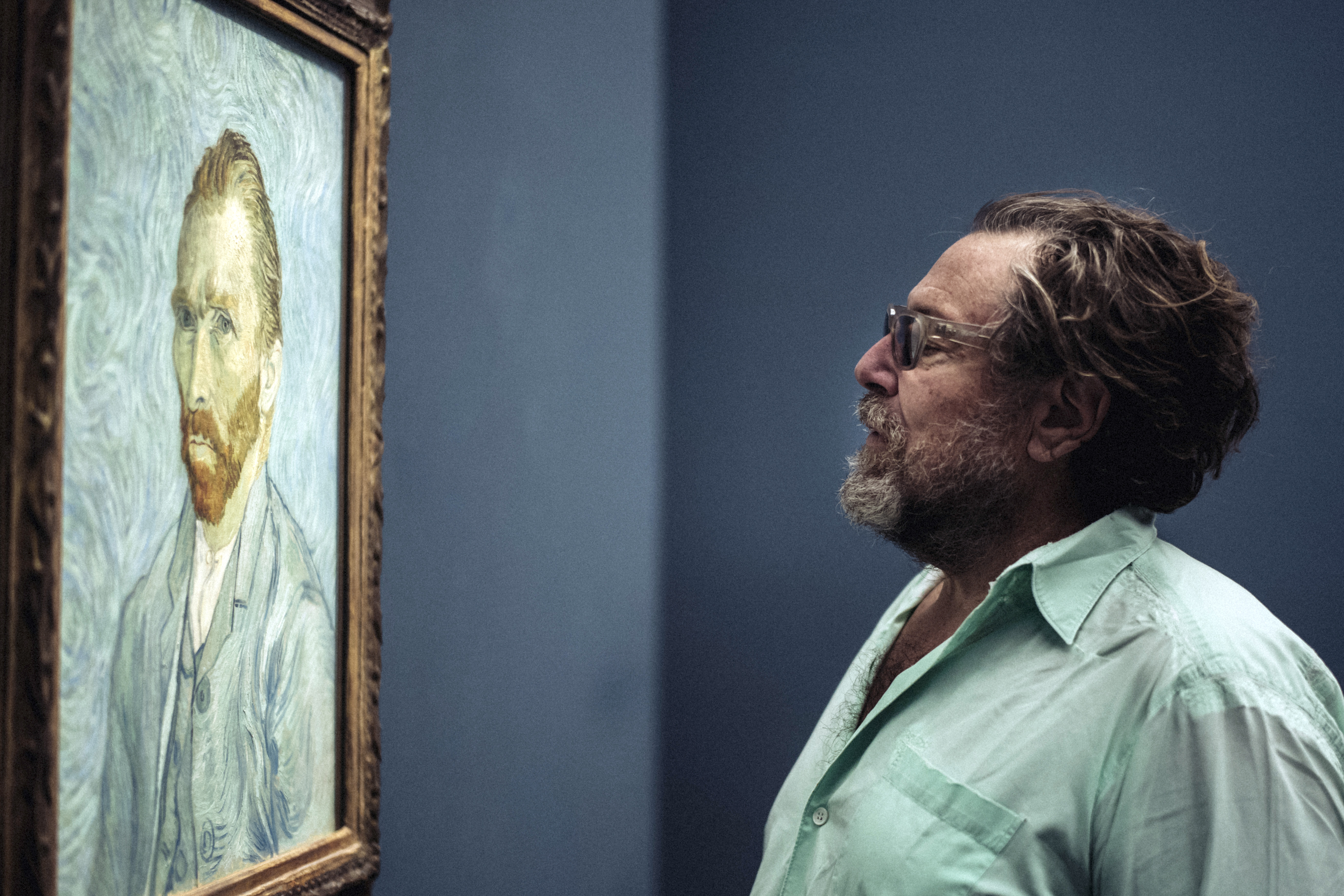 Painter-film director Julian Schnabel shown looking at a Vincent van Gogh self-portrait, in 2018.