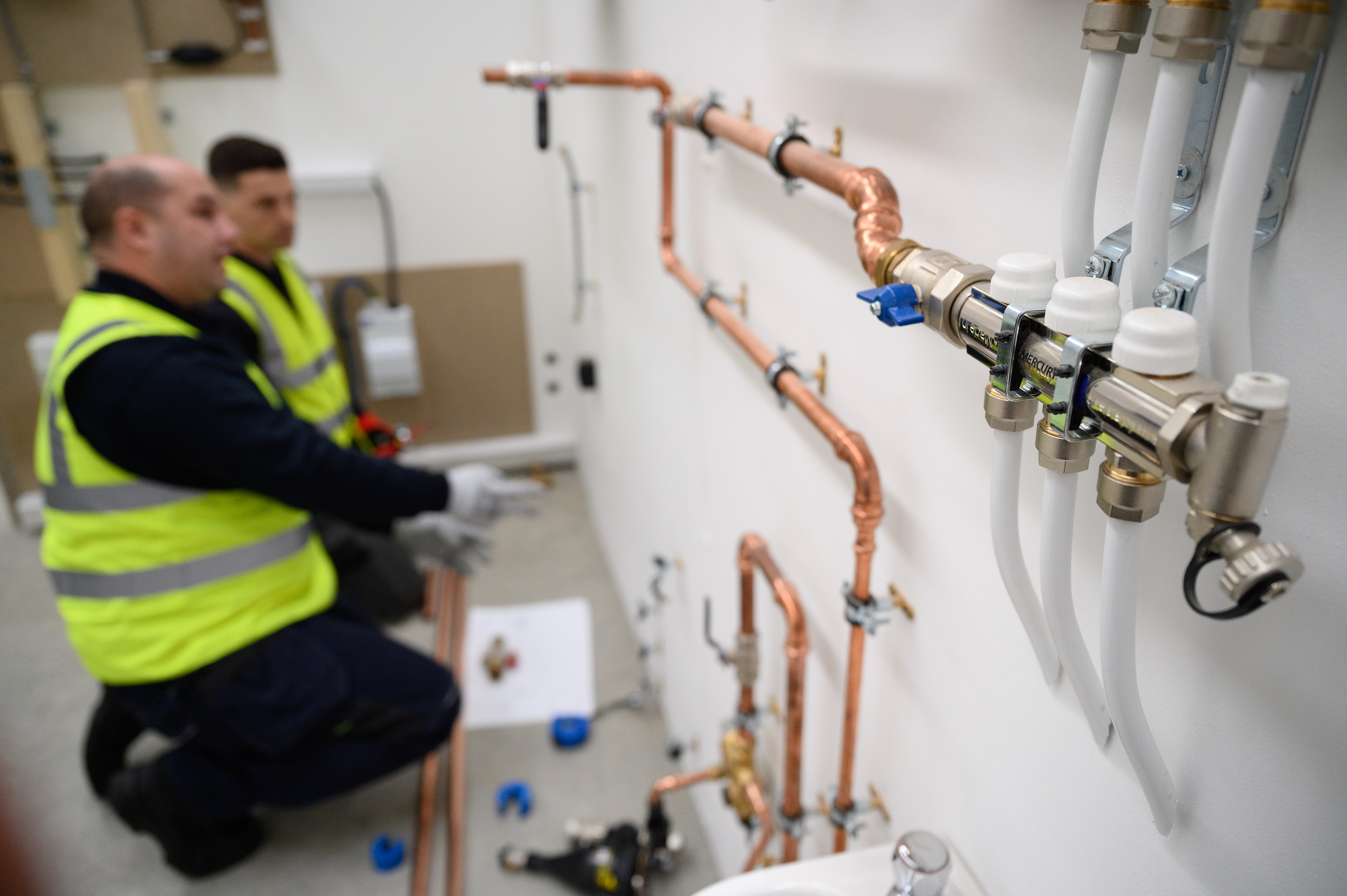 Plumbing engineers install pipework for a heat pump system at a training facility on Nov. 2 in Slough, England.