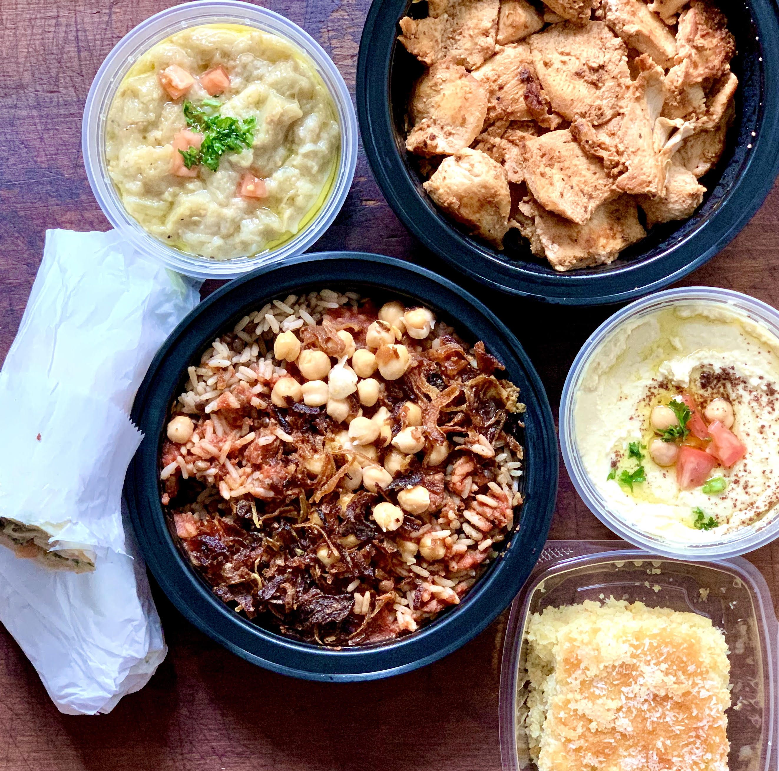 Zaaki Mediterranean Fine Food in Allston is serving its specialty dish, koshari (center), along with beef kufta roll-up (clockwise from left), baba ghanoush, shawarma chicken to top koshari, hummus, and a semolina-coconut cake called basboosa.