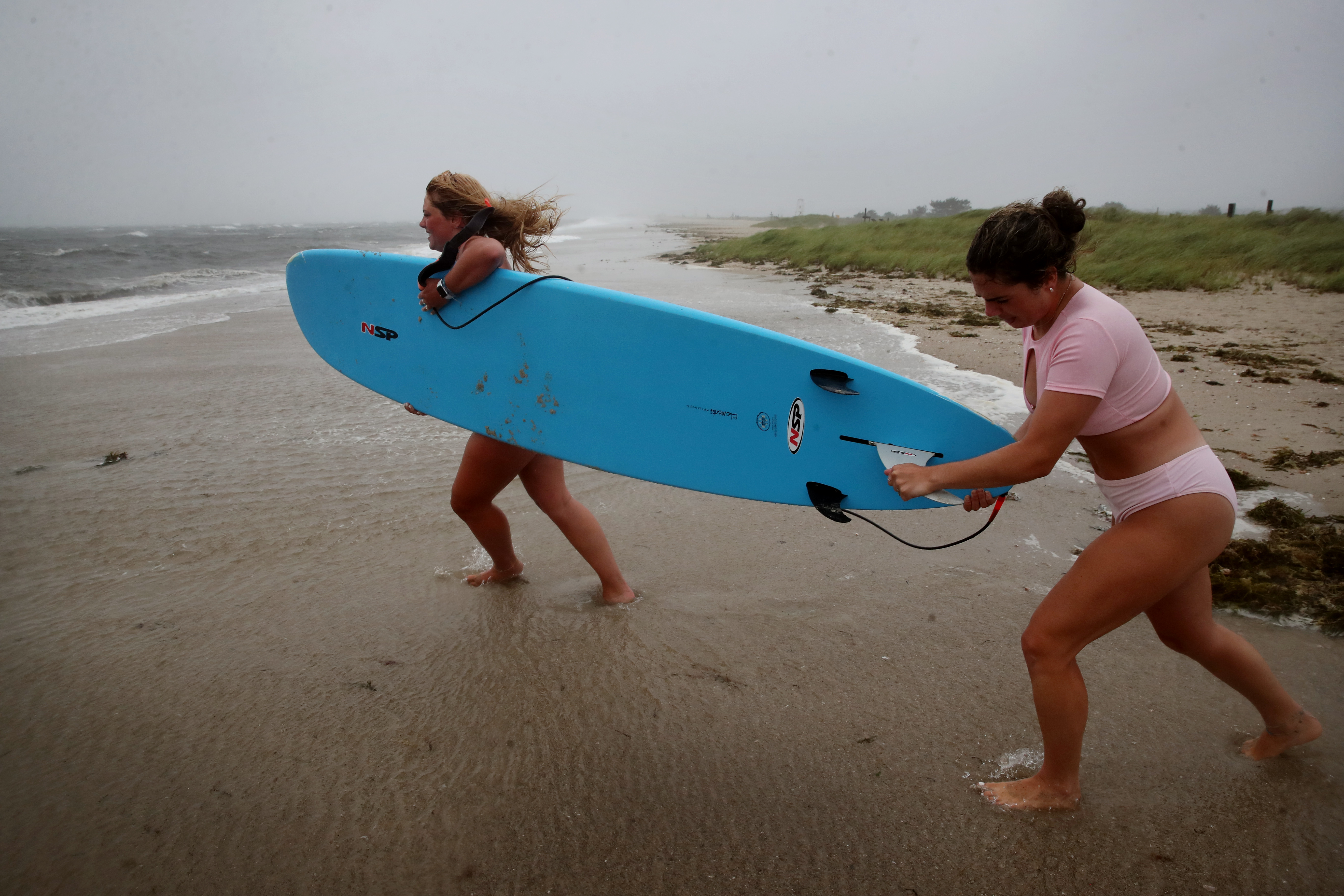 Lily Monahan, left, and Caitlin Kahaly arrive prepared to surf during Tropical Storm Elsa at West Dennis Beach.