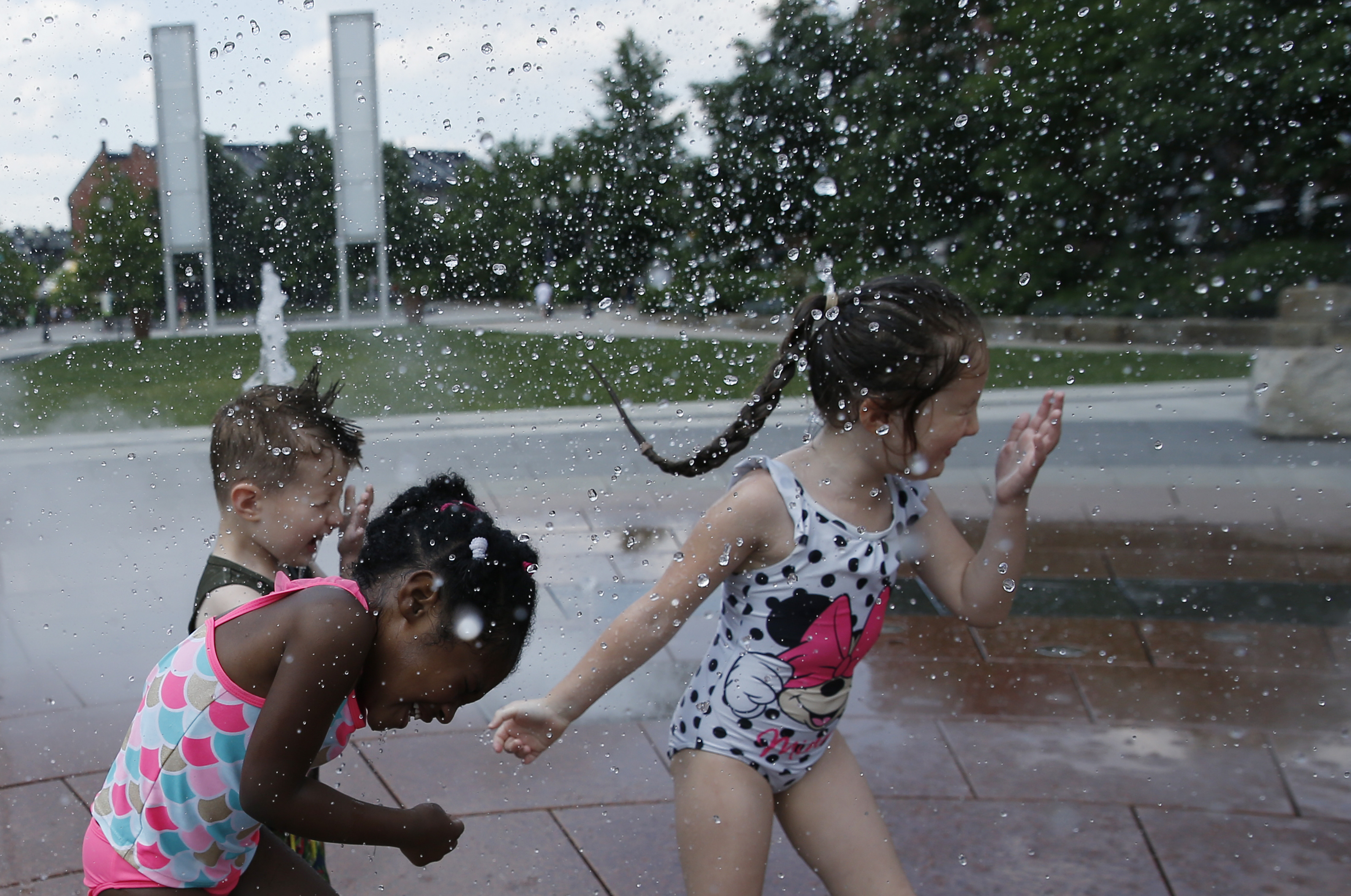 Four-year-old Jenasis Raper (left) ran into Rings Fountain with Rhys Clyde, 2, (center) and his sister, Freya, 4, on the Rose Kennedy Greenway Monday.