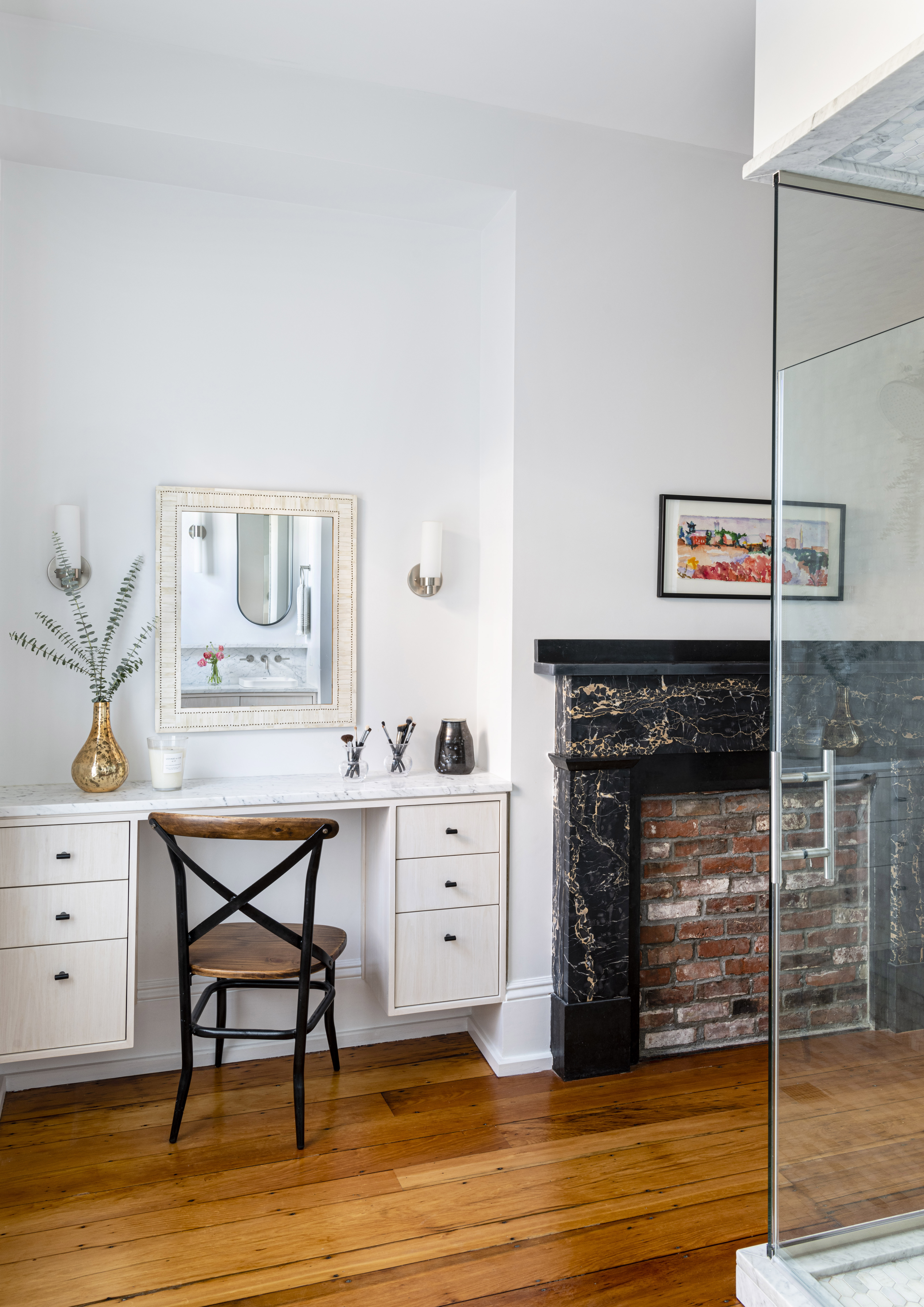 Axis Woodworking crafted the whitewashed ash makeup vanity and the main vanity in the couple’s en suite bath. The wife’s grandmother painted the watercolor landscape above the restored Portero marble mantelpiece.
