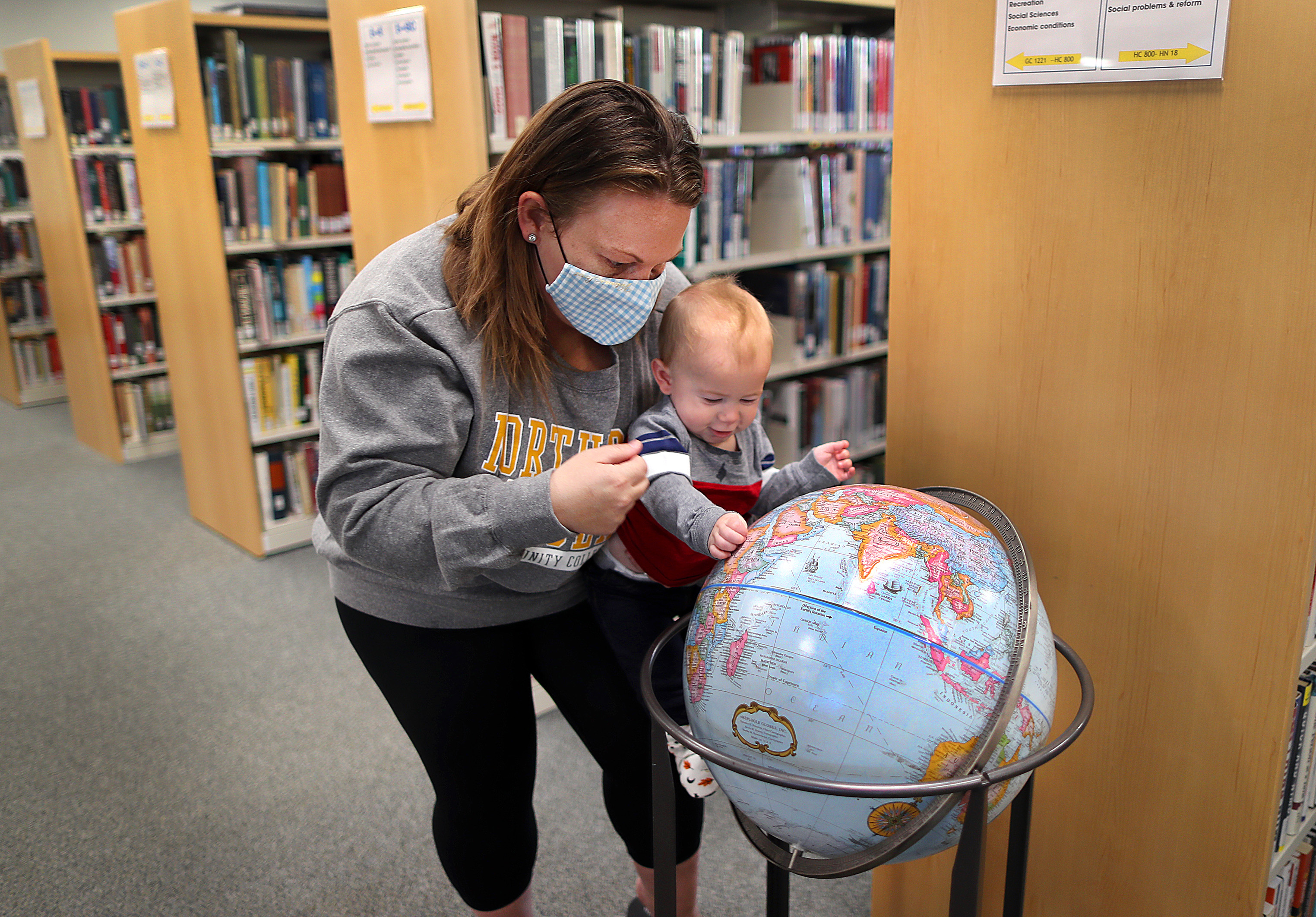 Navy veteran Crystal Chandler is a student at Northern Essex Community College. She shows her 7-month-old son, August, a globe in the college library.