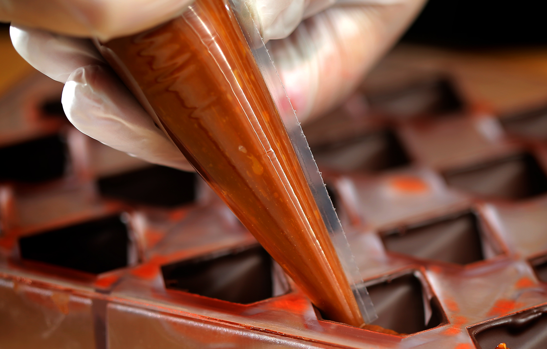 Gal adds filling to a tray mold of bonbons.